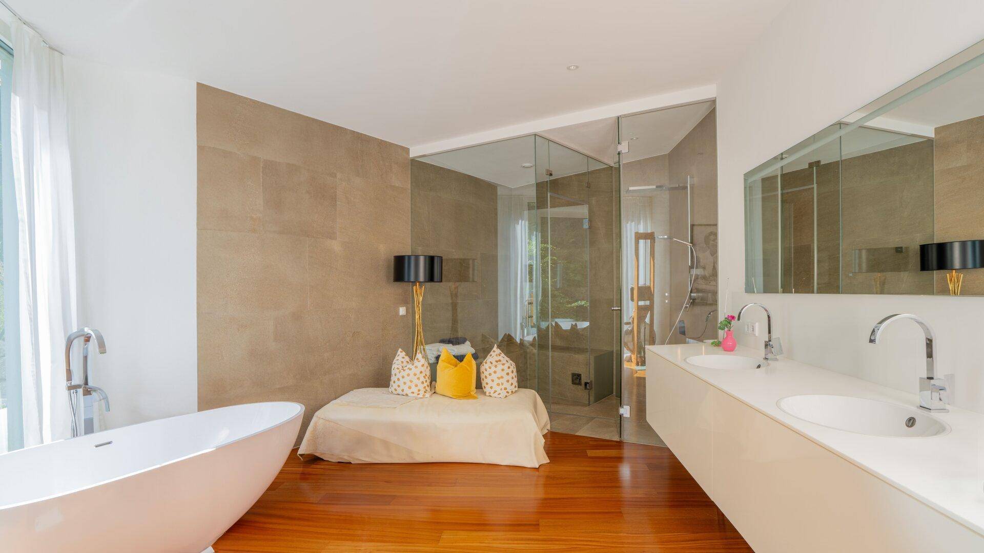 Luxuriöses Badezimmer mit freistehender Badewanne, Doppelwaschbecken und begehbarer Glasdusche.