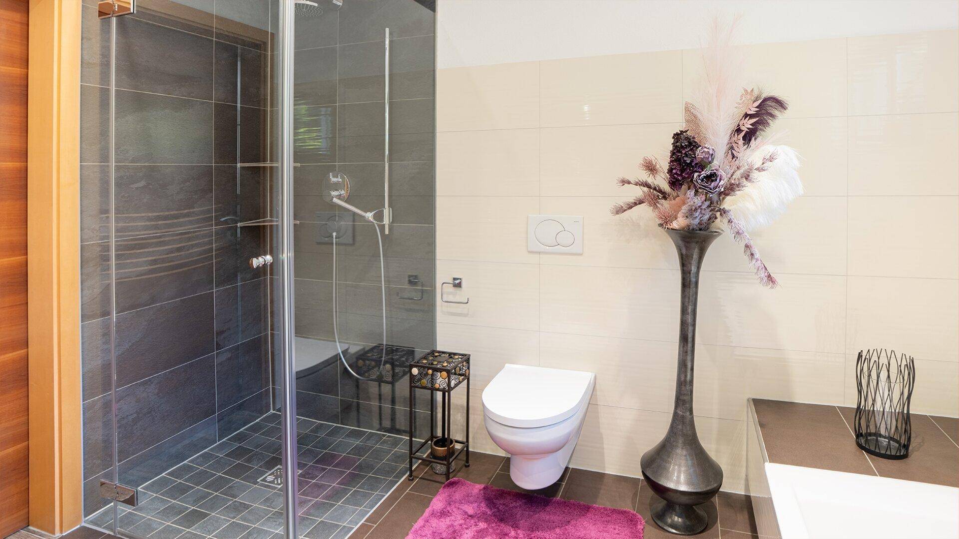 Elegantes Badezimmer mit großer Duschkabine, Wand-WC und stilvoller Dekoration.