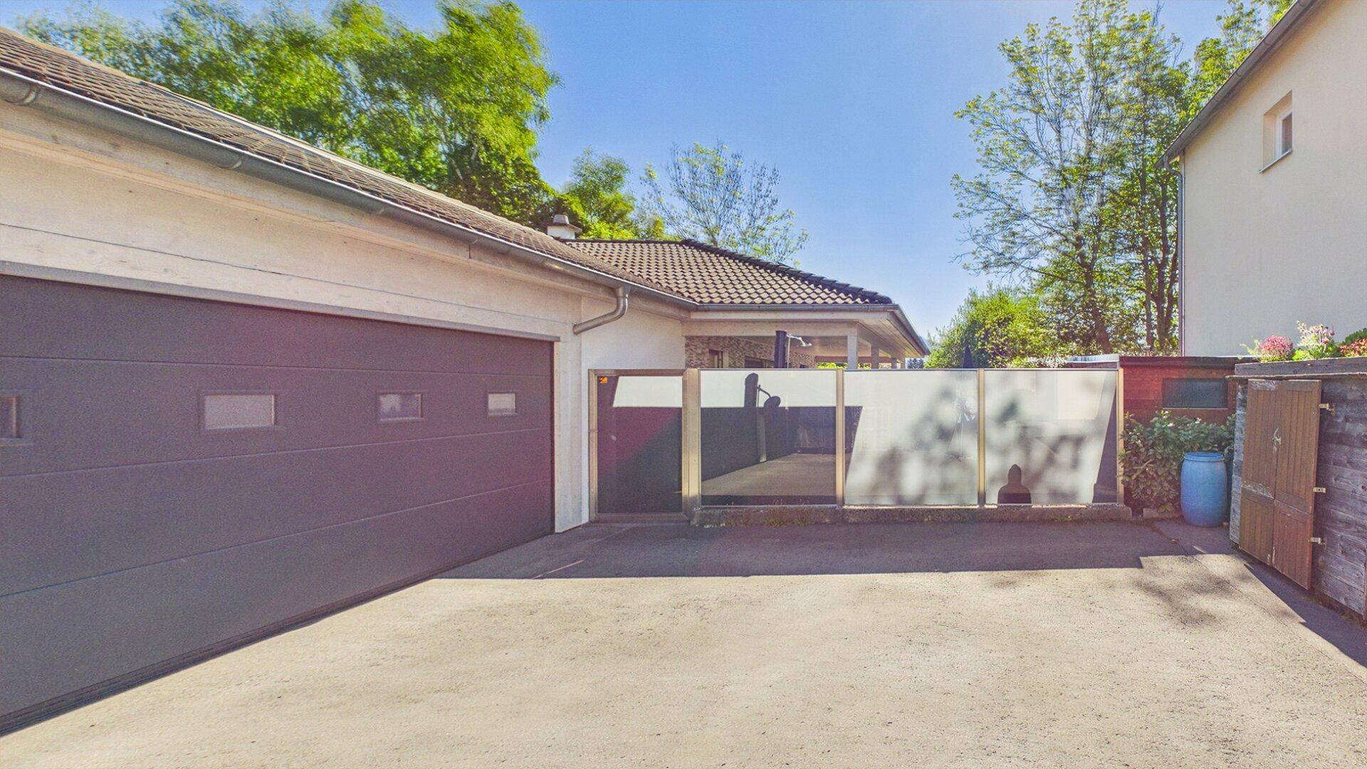 Geräumige Garage mit breitem Einfahrtsbereich und moderner Sichtschutzwand im Hintergrund.