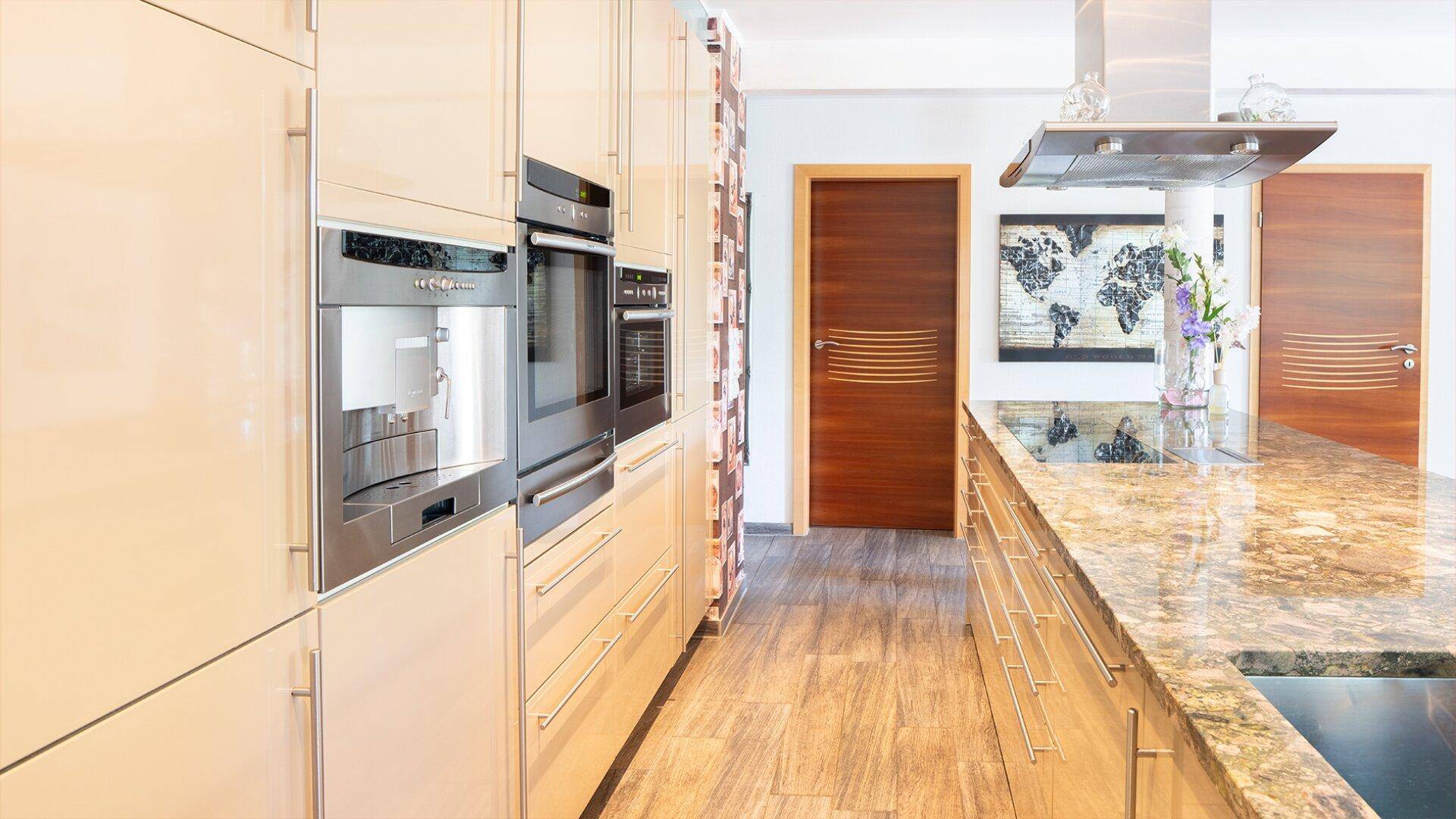 Elegante Küchenzeile mit integriertem Kaffeevollautomaten und Backofen, sowie Holztüren.