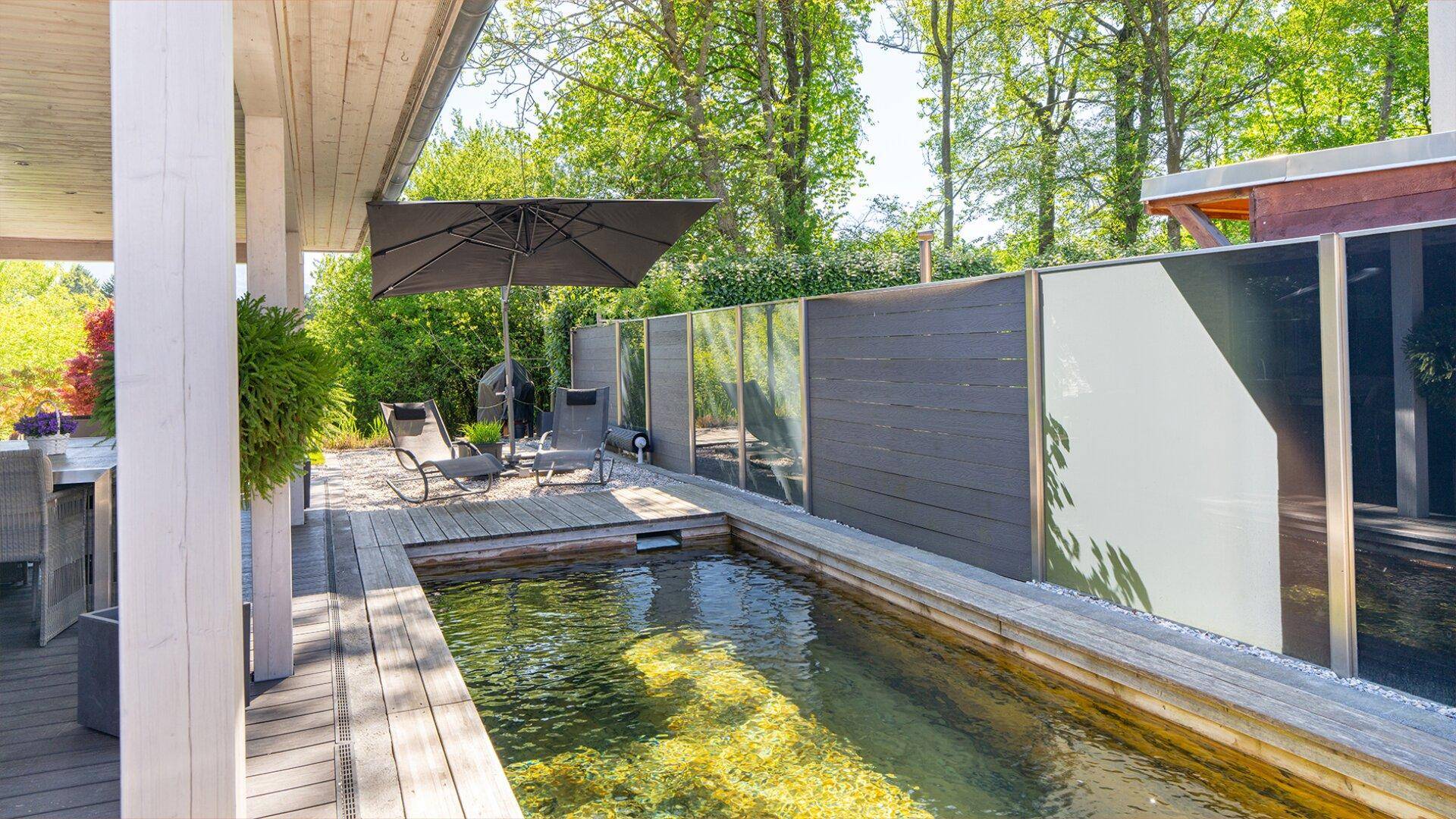 Entspannungsbereich auf der Terrasse mit Liegestühlen und einem ruhigen Wasserbecken.