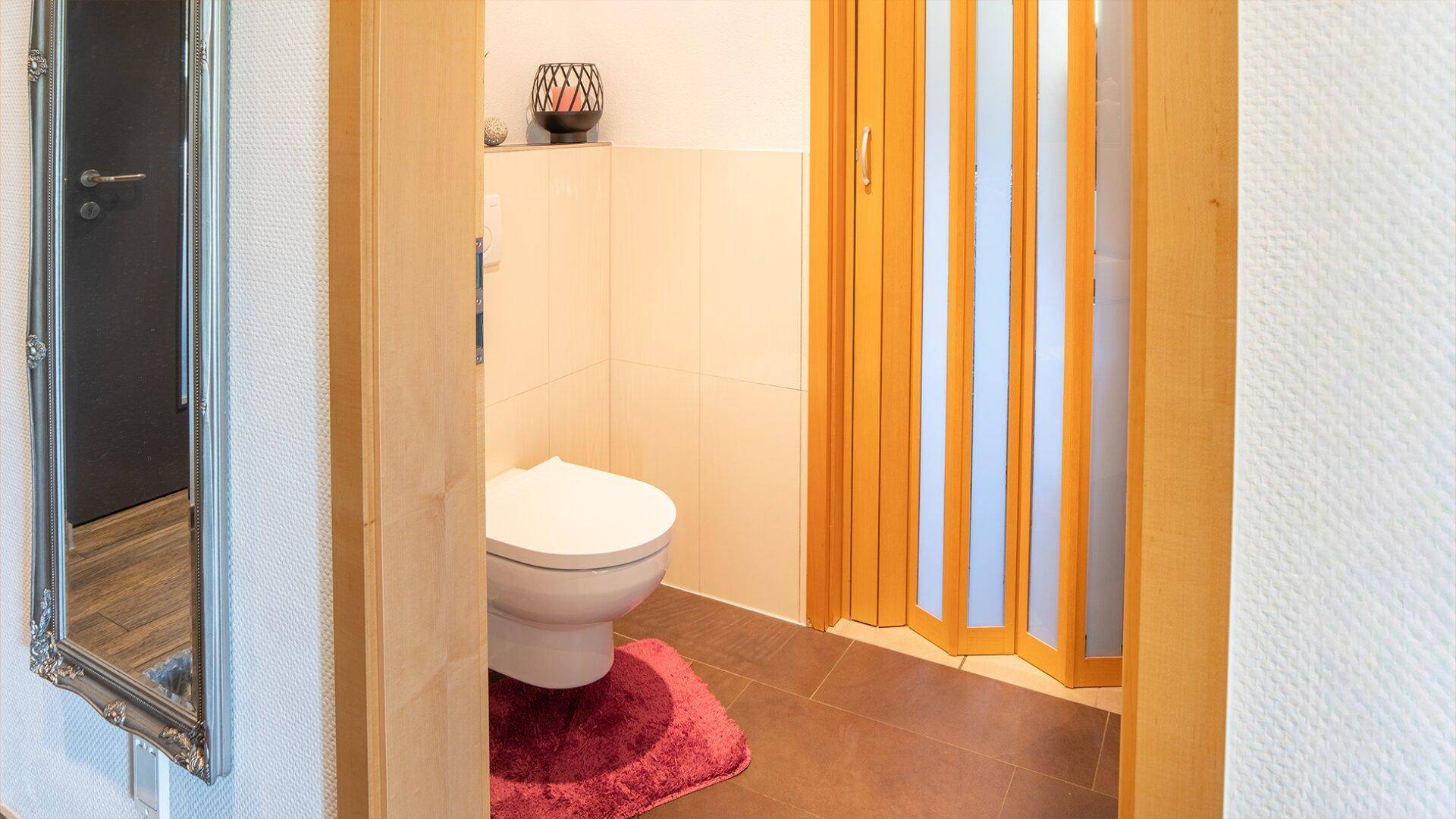 Kleines Gäste-WC mit Wand-WC und praktischer Falttür, ideal für Besucher.
