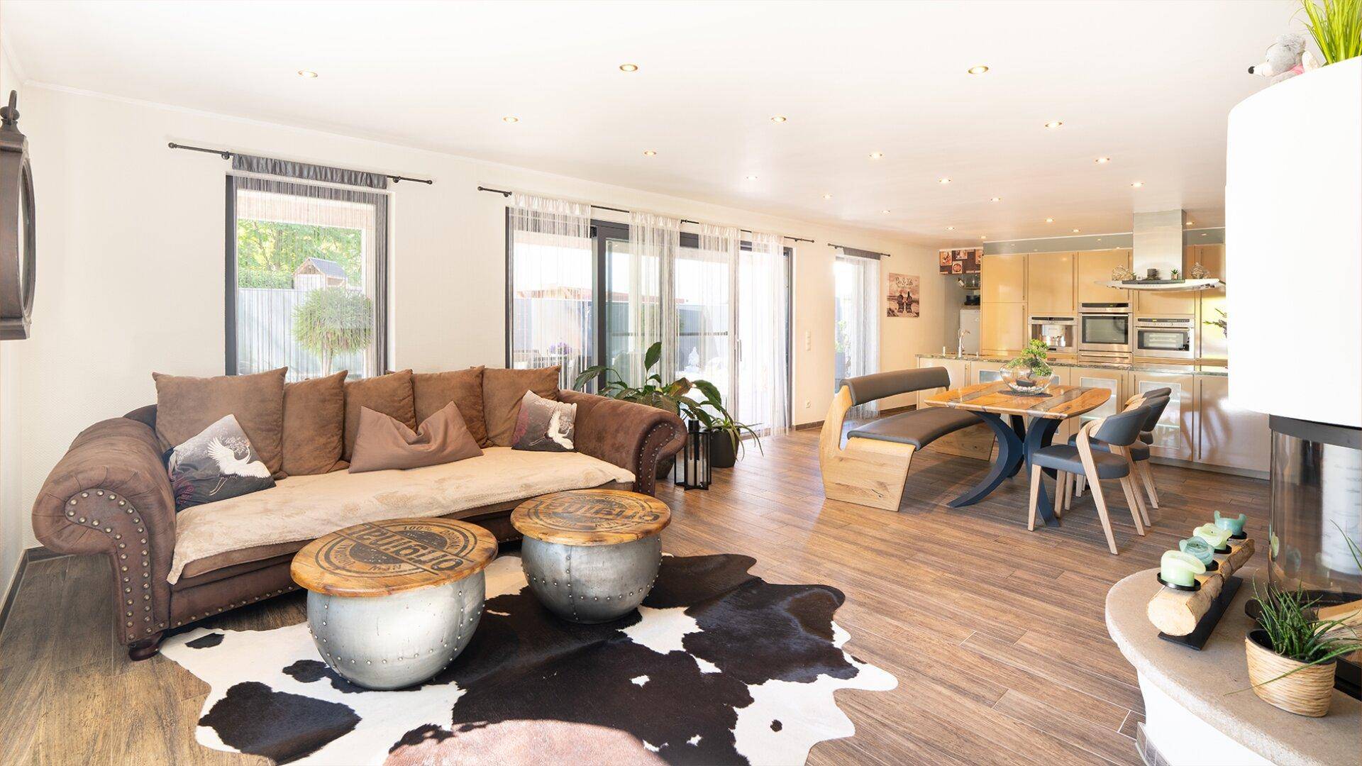Offener Wohn-Essbereich mit integrierter Küche, Kamin und Zugang zur Terrasse.