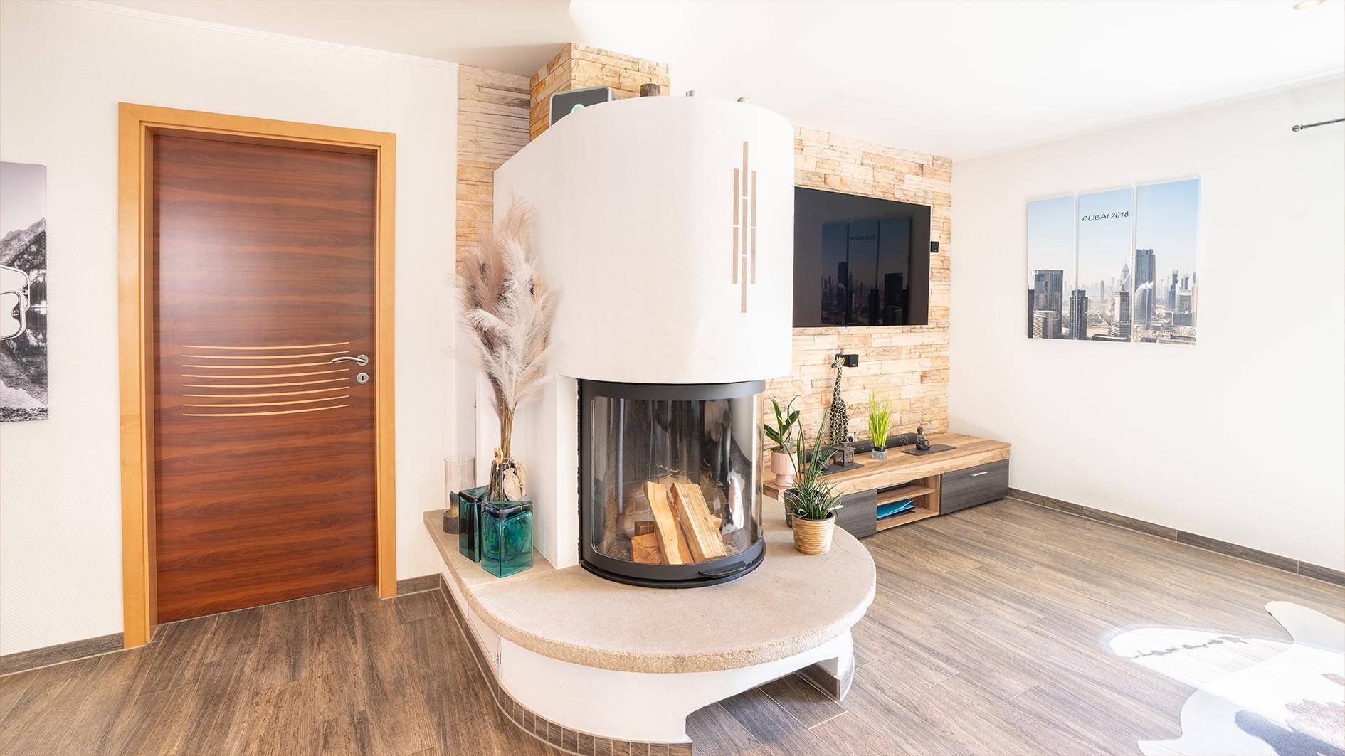 Moderner Kamin als Mittelpunkt des Wohnzimmers mit Holzboden und Steinwandakzenten.