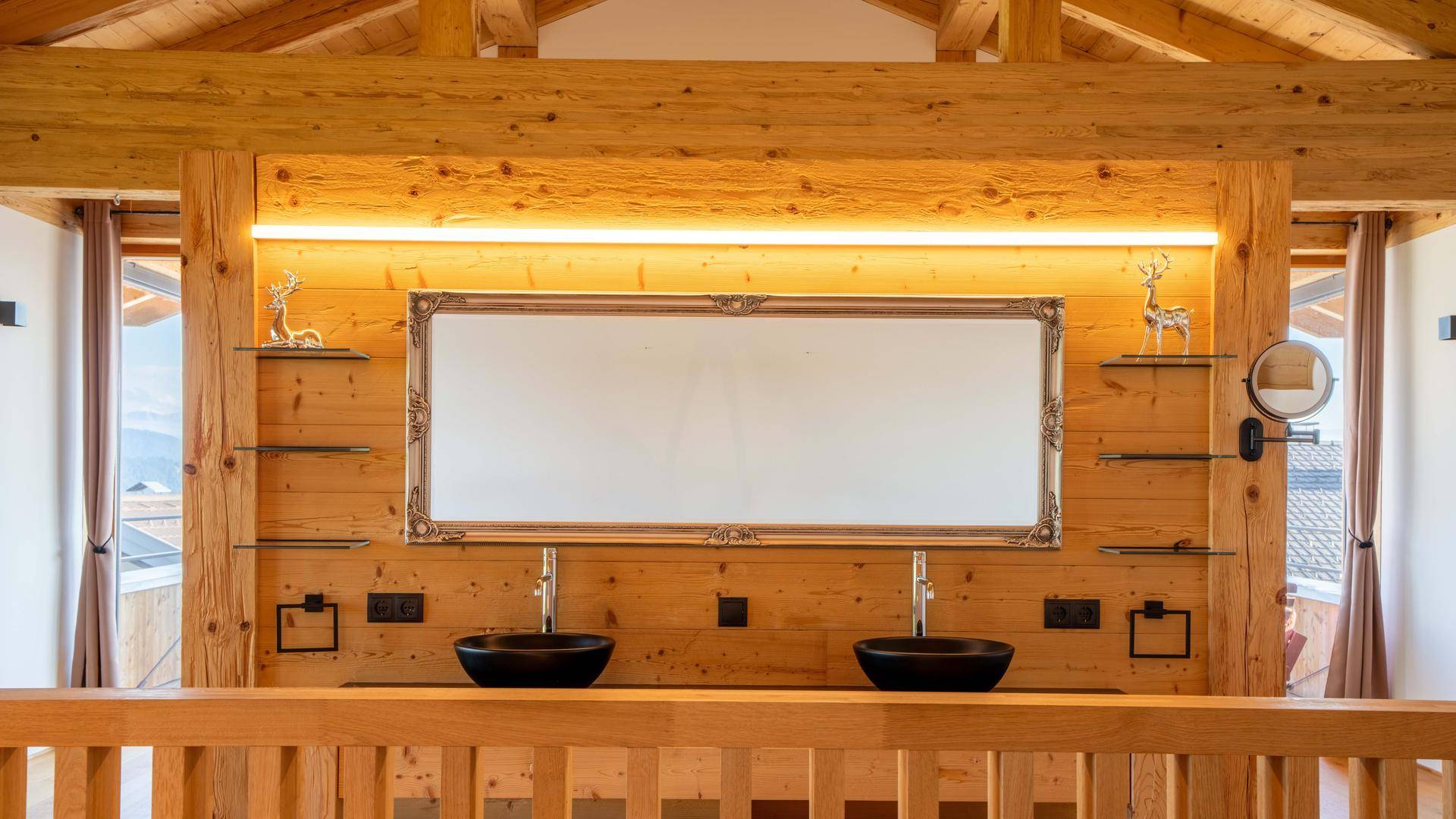Rustikales Badezimmer mit Doppelwaschbecken, großem Spiegel und Holzwänden unter Dachschrägen.