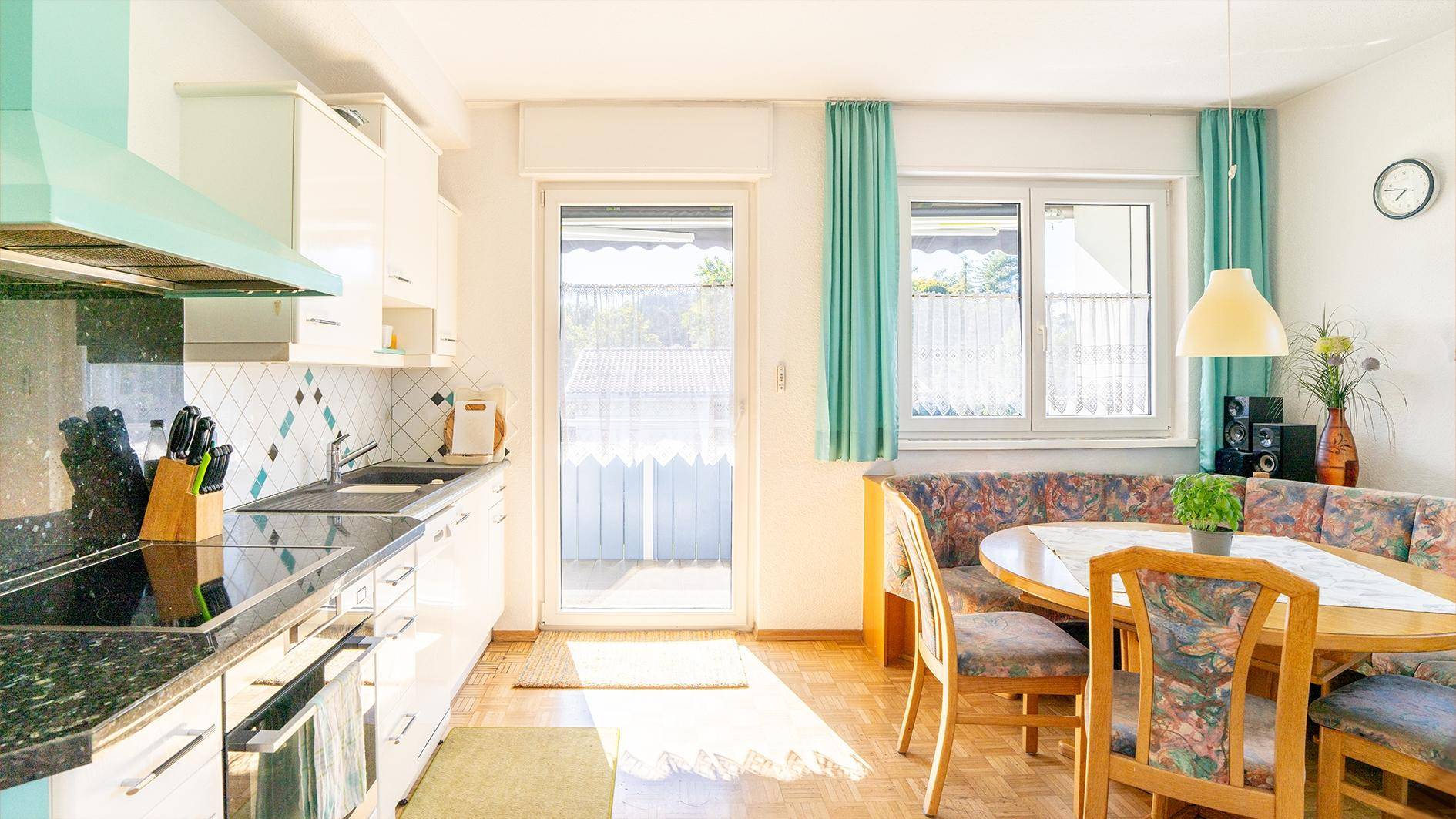 Helle Küche mit Essbereich, Granitarbeitsplatten und Zugang zum Balkon.