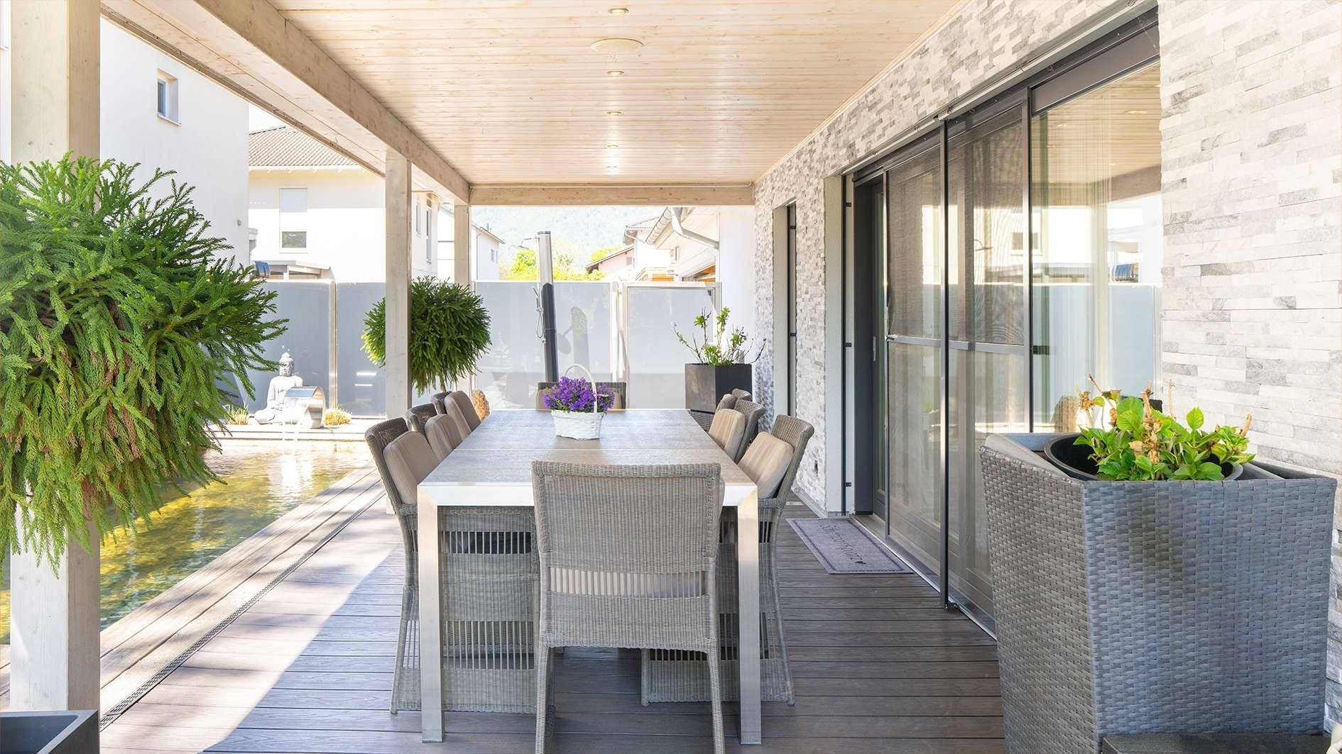 Geräumige überdachte Terrasse mit Essbereich und Schiebetüren zum Wohnbereich des Hauses.