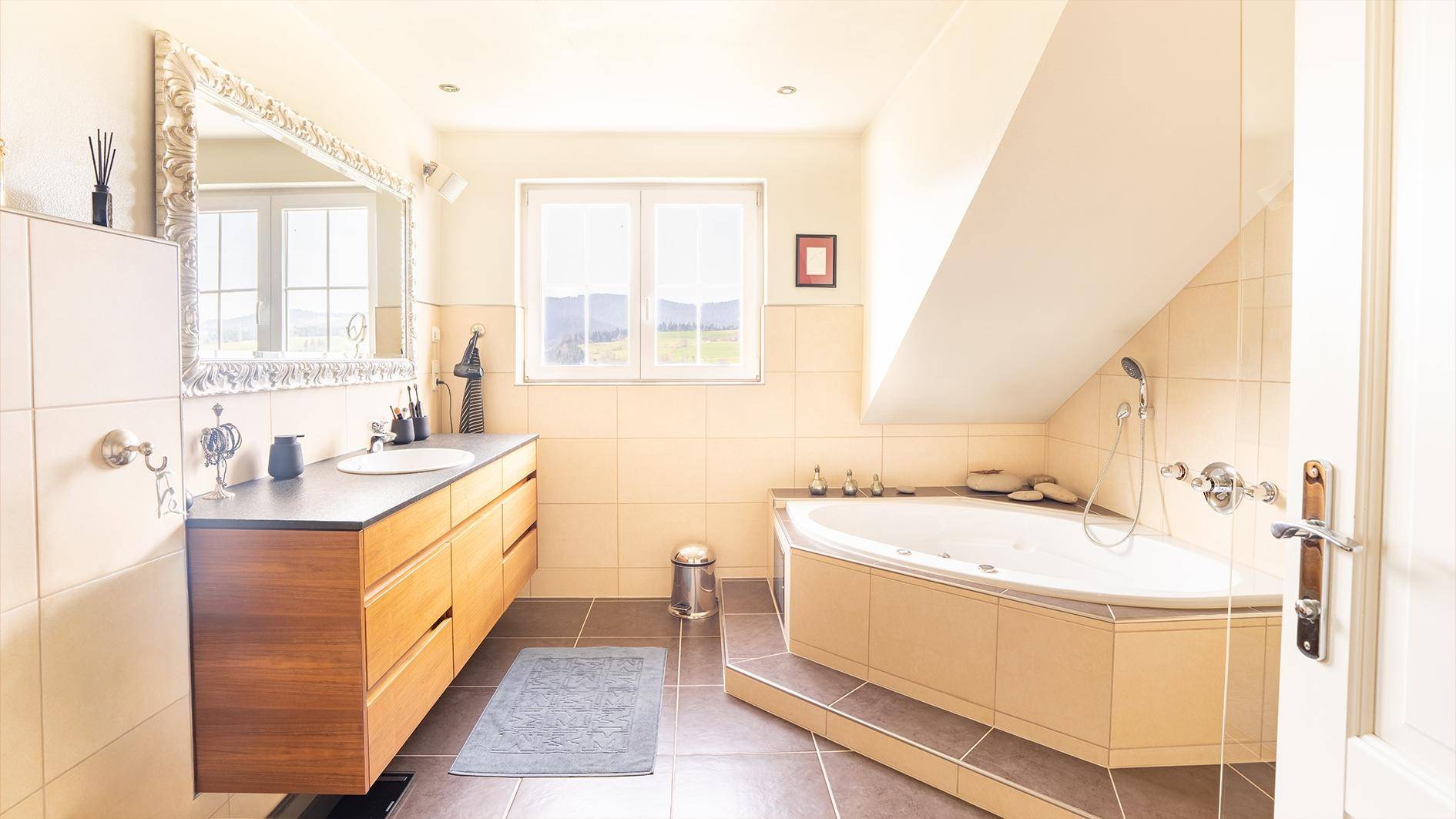 Großes Badezimmer mit Eckbadewanne, Doppelwaschbecken und Fenster mit Weitblick.