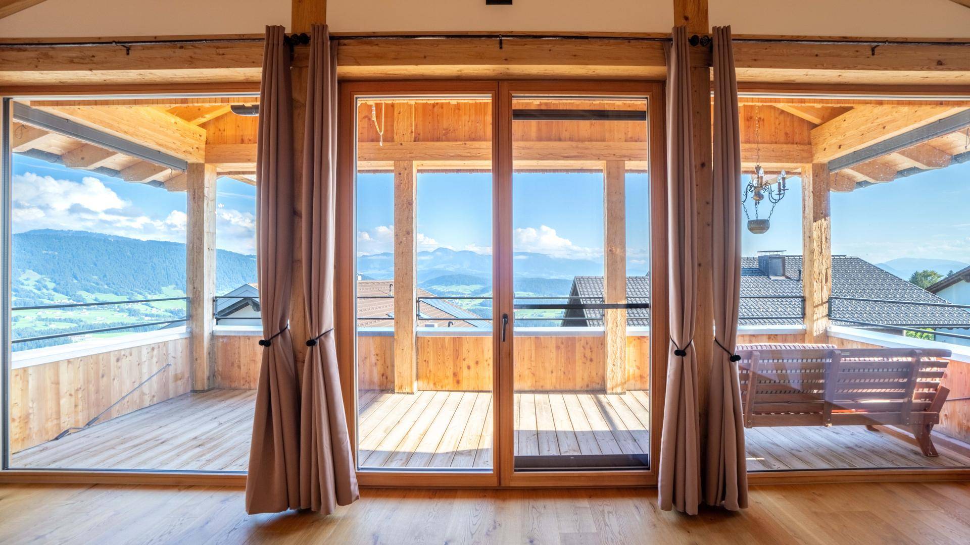 Helles Zimmer mit breitem Balkonzugang und Panoramablick auf die umliegende Berglandschaft.