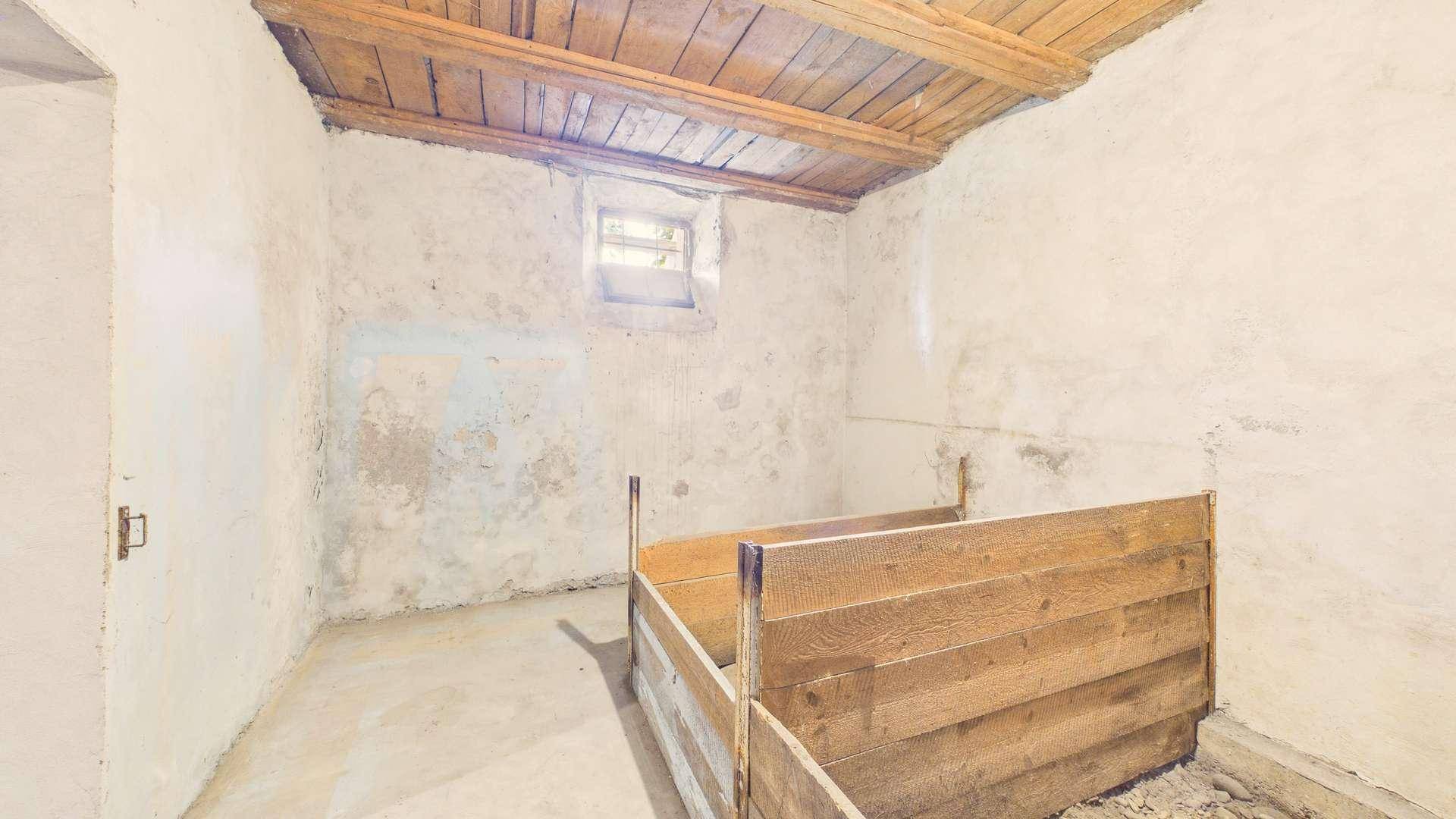 Rustikaler Kellerraum mit Holzbalkendecke und Betonboden, bereit zur Nutzung.