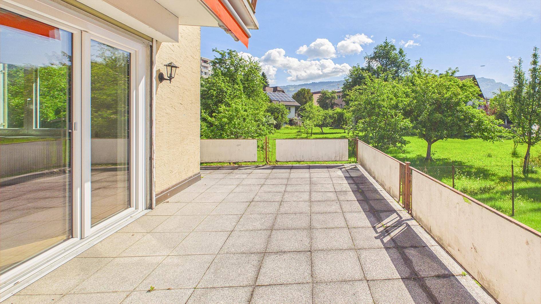 Große, geflieste Terrasse mit Blick ins Grüne, ideal für Entspannung im Freien.