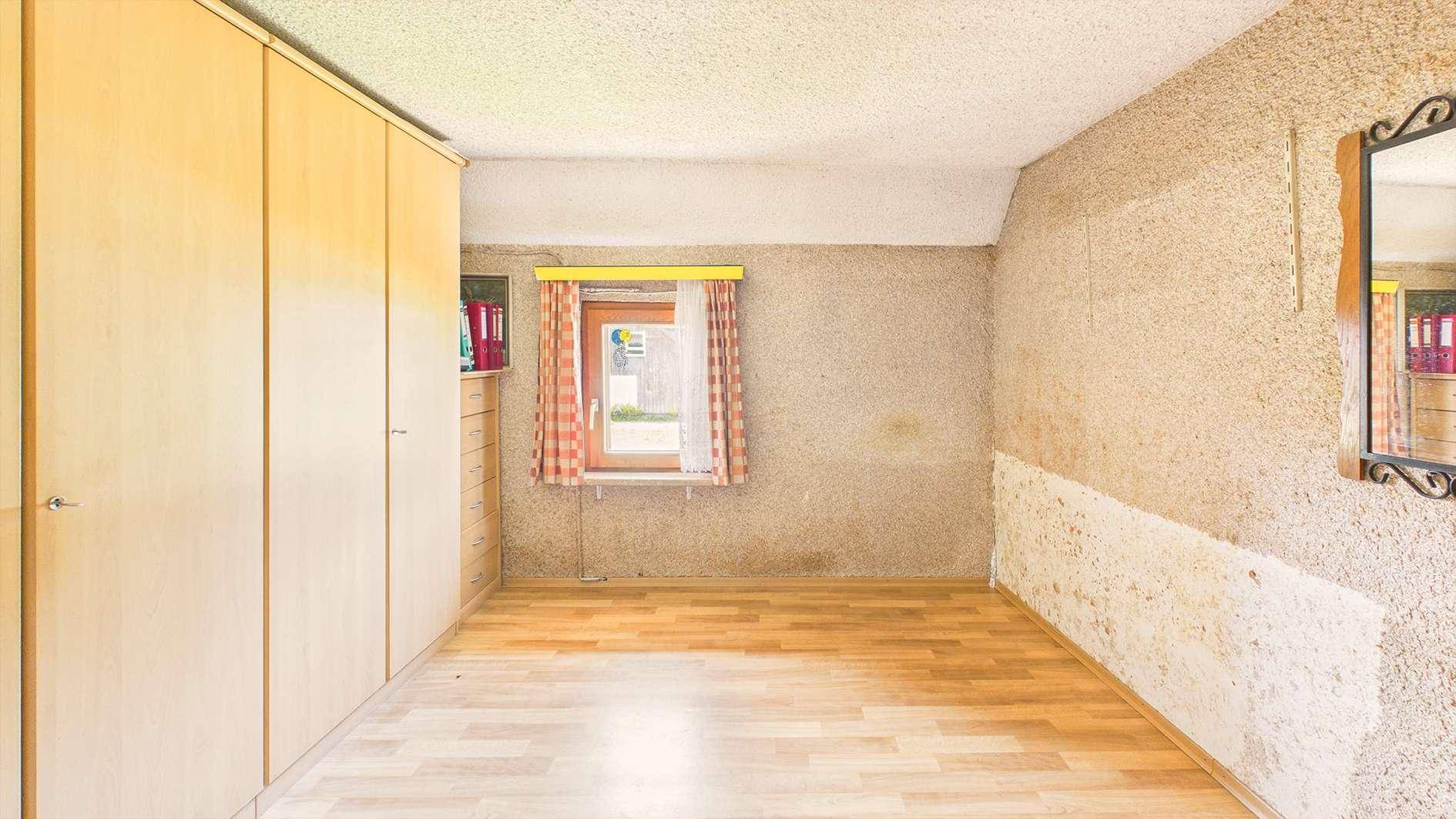 Leerer Raum mit Einbauschränken, Holzboden und strukturierten Wänden.