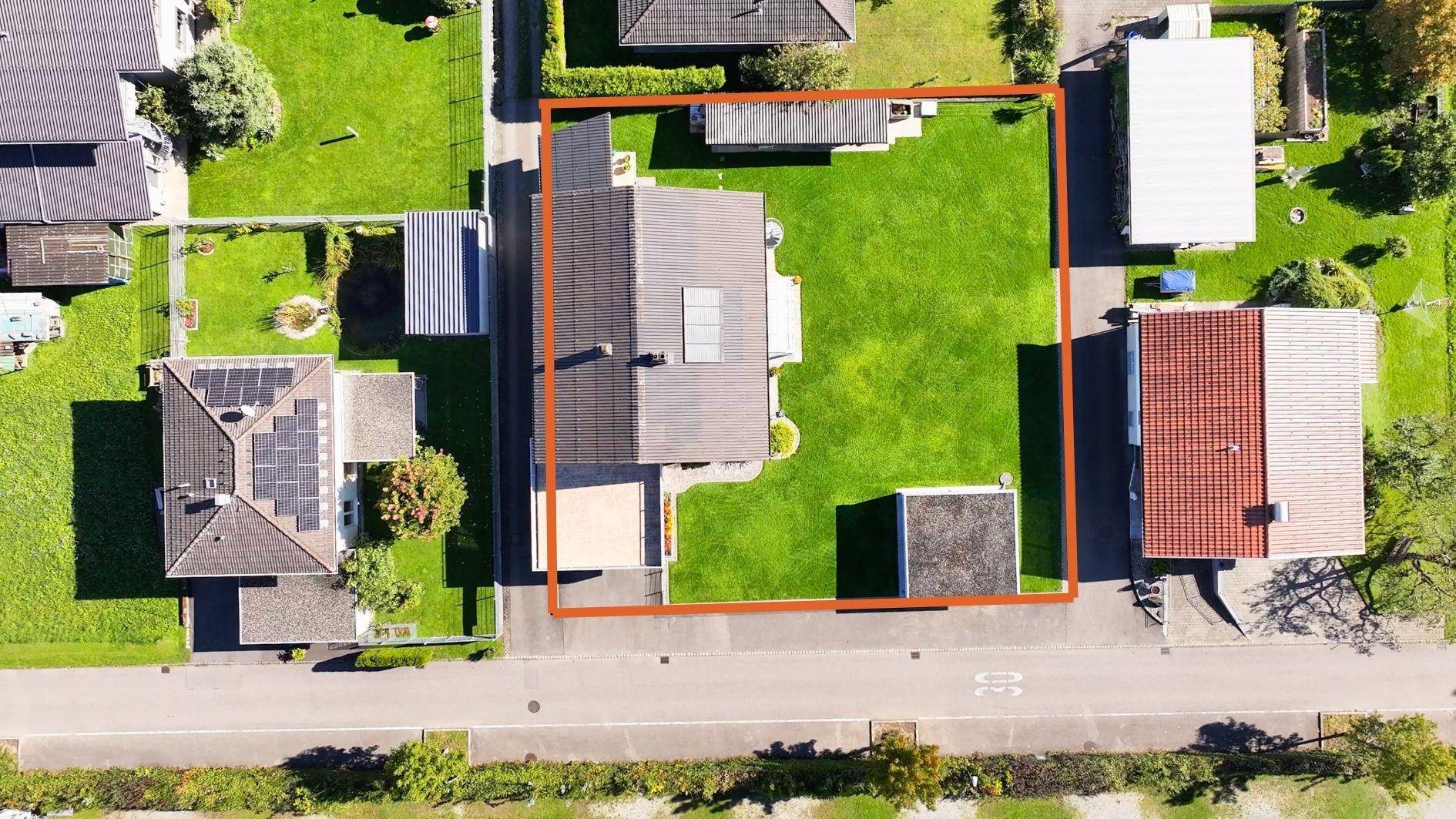 Luftaufnahme eines Einfamilienhauses mit großem Garten, Rasenfläche und umrandetem Grundstück.