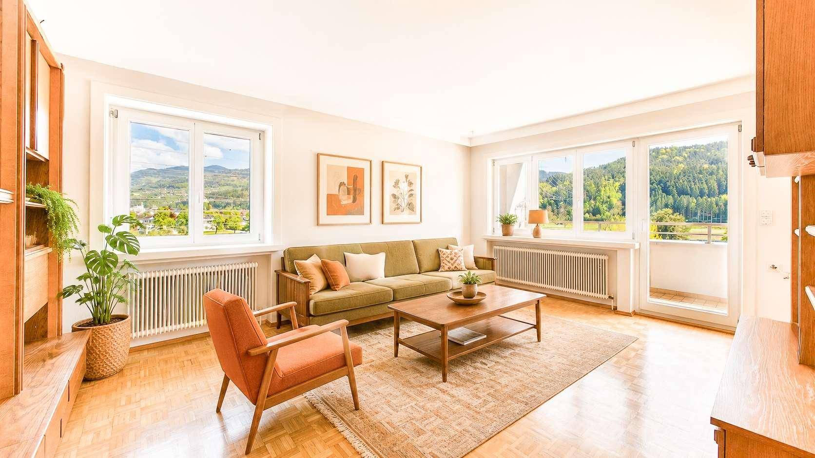 Gemütliches Wohnzimmer mit Holzboden, bequemer Couch und weitem Blick ins Grüne.