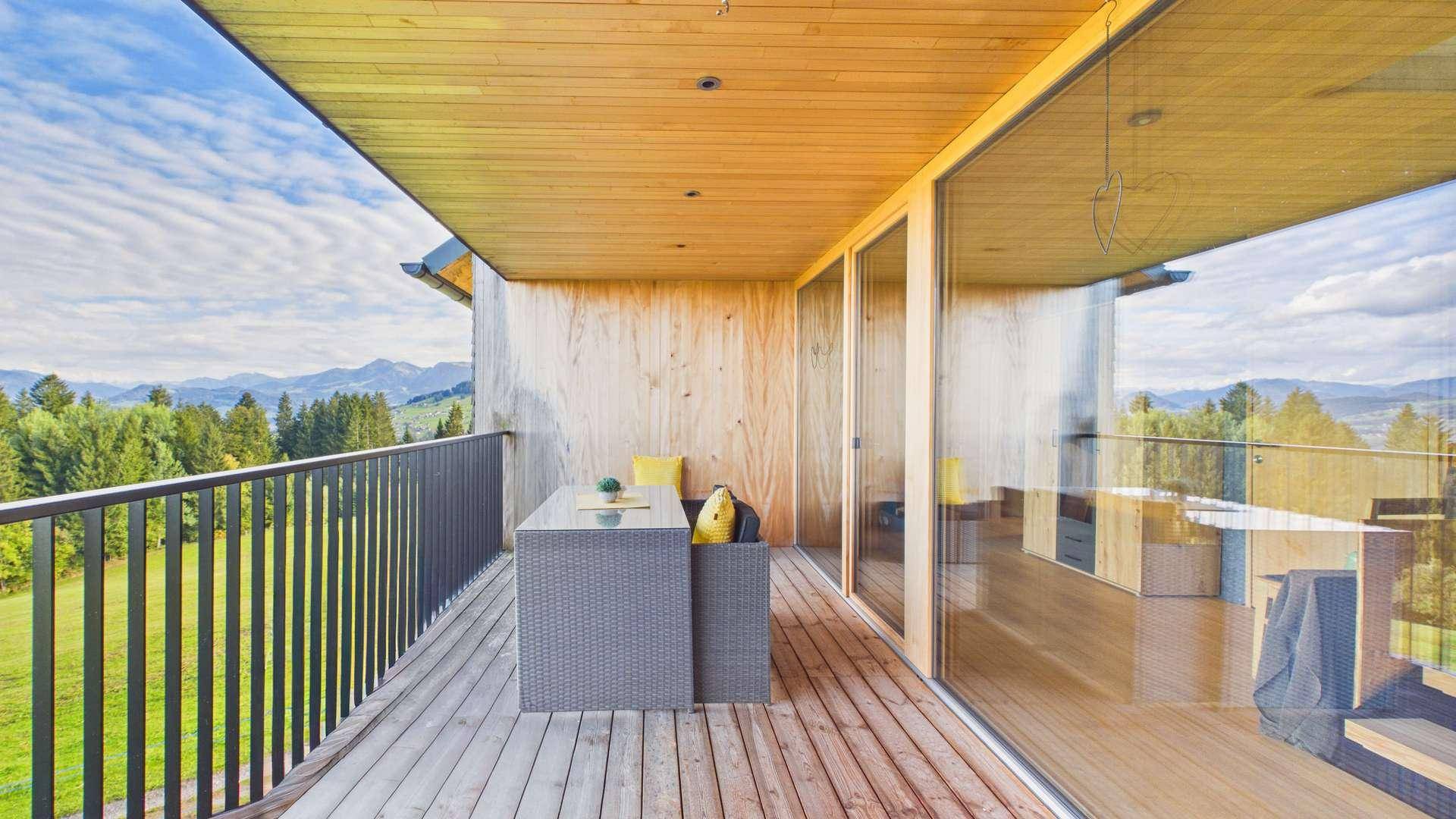 Moderner Balkon mit Holzboden und Lounge-Möbeln, ideal zum Entspannen mit Bergblick.