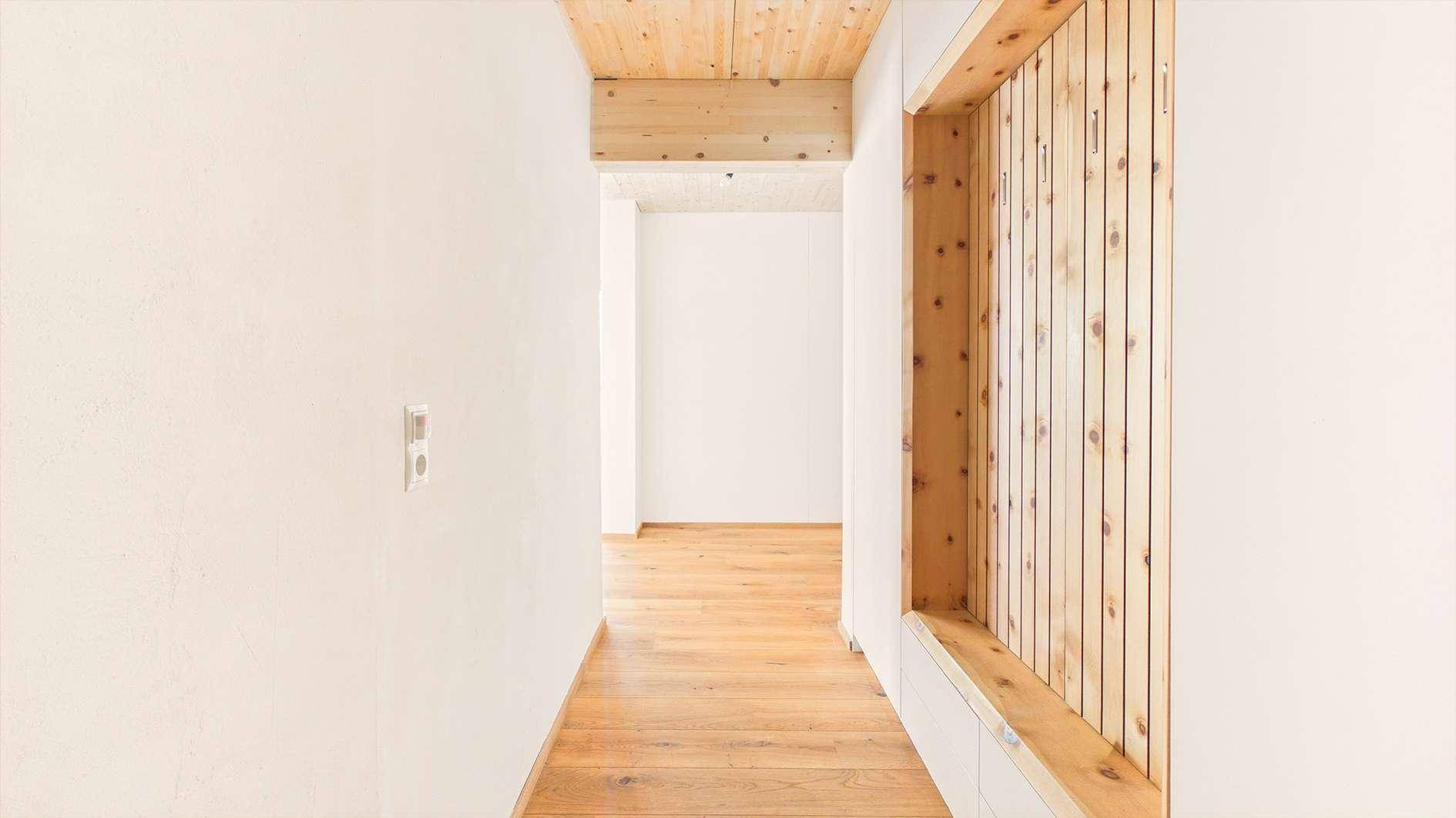 Heller Flur mit Holzboden, Holzdecke und einer dekorativen Holzverkleidung.