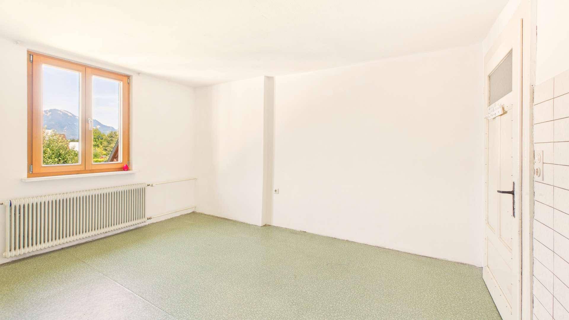 Geräumiges Zimmer mit grünem Bodenbelag und Fenster mit Bergblick.