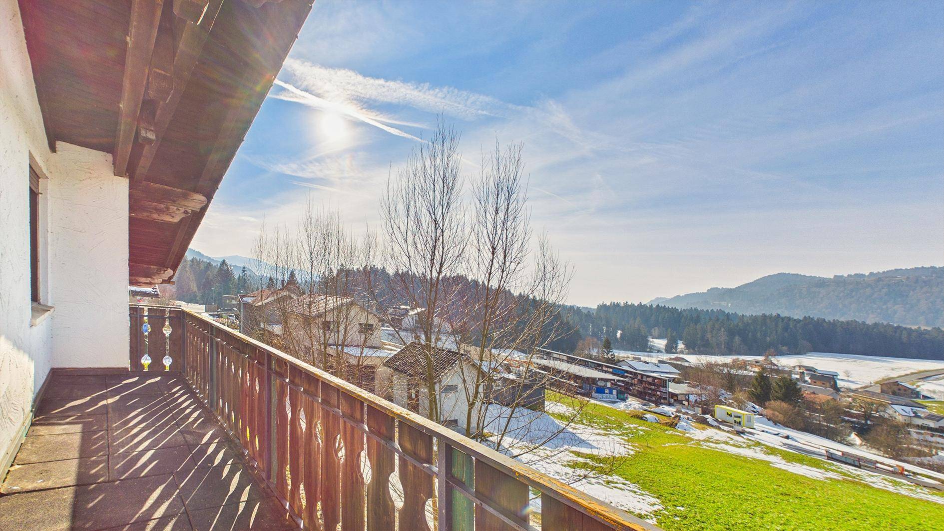 Weitläufiger Ausblick vom Balkon auf die verschneite Landschaft und die umliegenden Berge.