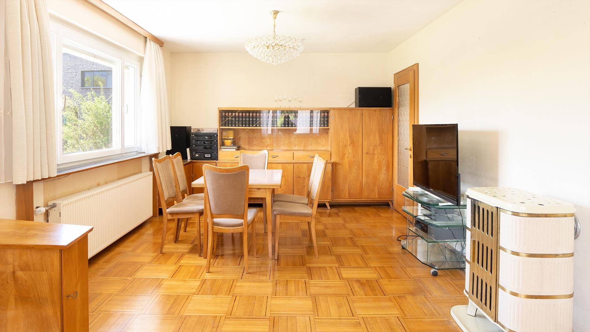 Geräumiger Essbereich mit Holzboden, Esstisch und einem dekorativen Kachelofen.
