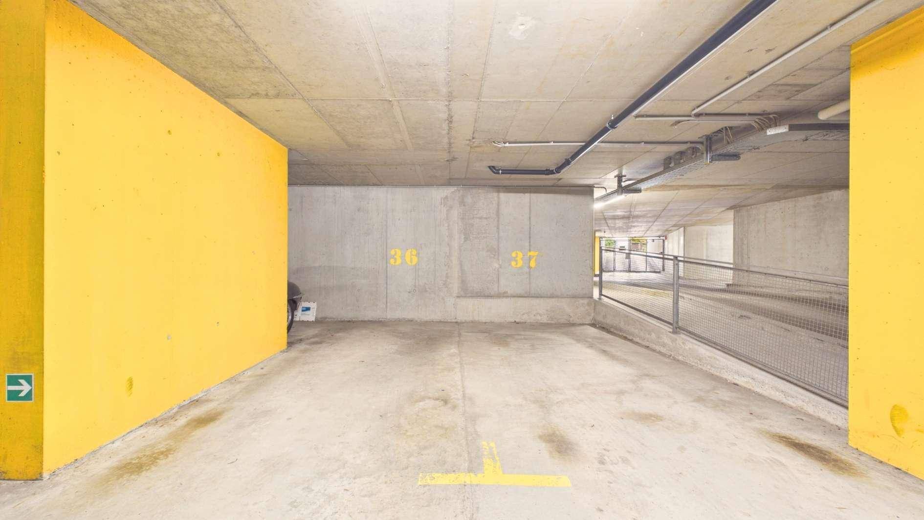 Tiefgarage mit Betonwänden, gelben Markierungen und Zufahrtsrampe.