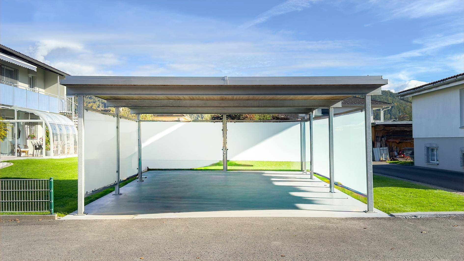 Moderner Carport mit Metallkonstruktion und seitlichen Sichtschutzwänden für zwei Fahrzeuge.