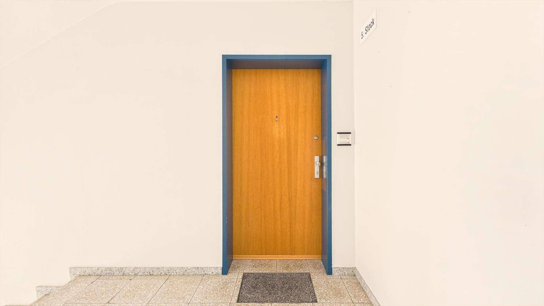 Eingangstür einer Wohnung im 3. Stock mit blauer Zarge und Fußmatte.