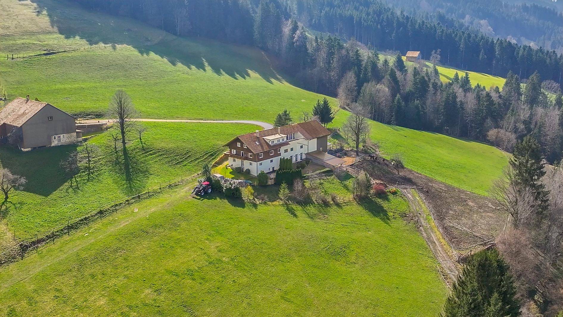 Luftaufnahme des Anwesens, eingebettet in eine weite, grüne Hügellandschaft.