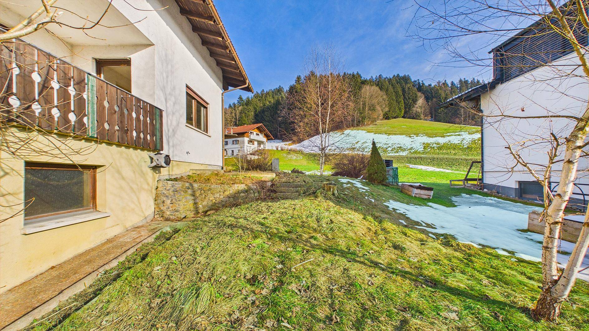 Blick auf das Haus mit kleinem Balkon und Gartenbereich in einer ländlichen Umgebung.