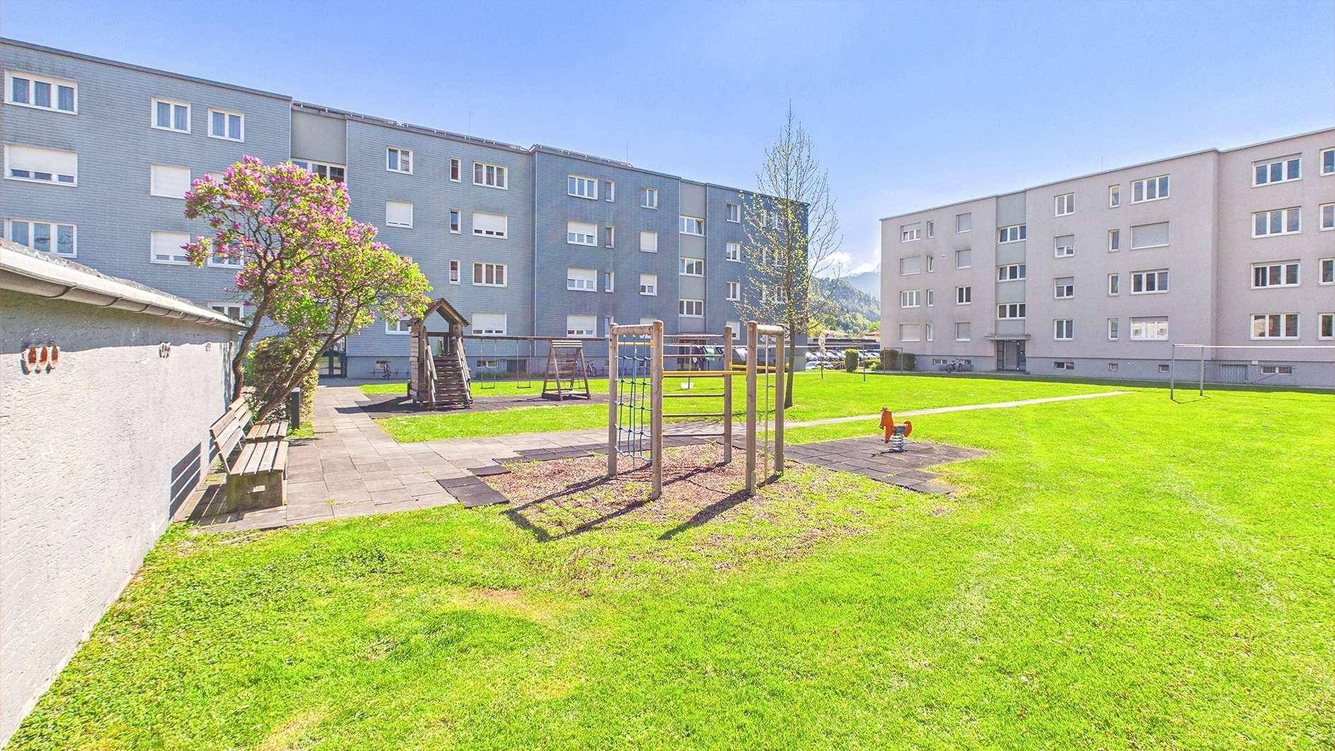 Großer Gemeinschaftsgarten mit Spielplatz und Grünflächen zwischen Wohngebäuden.