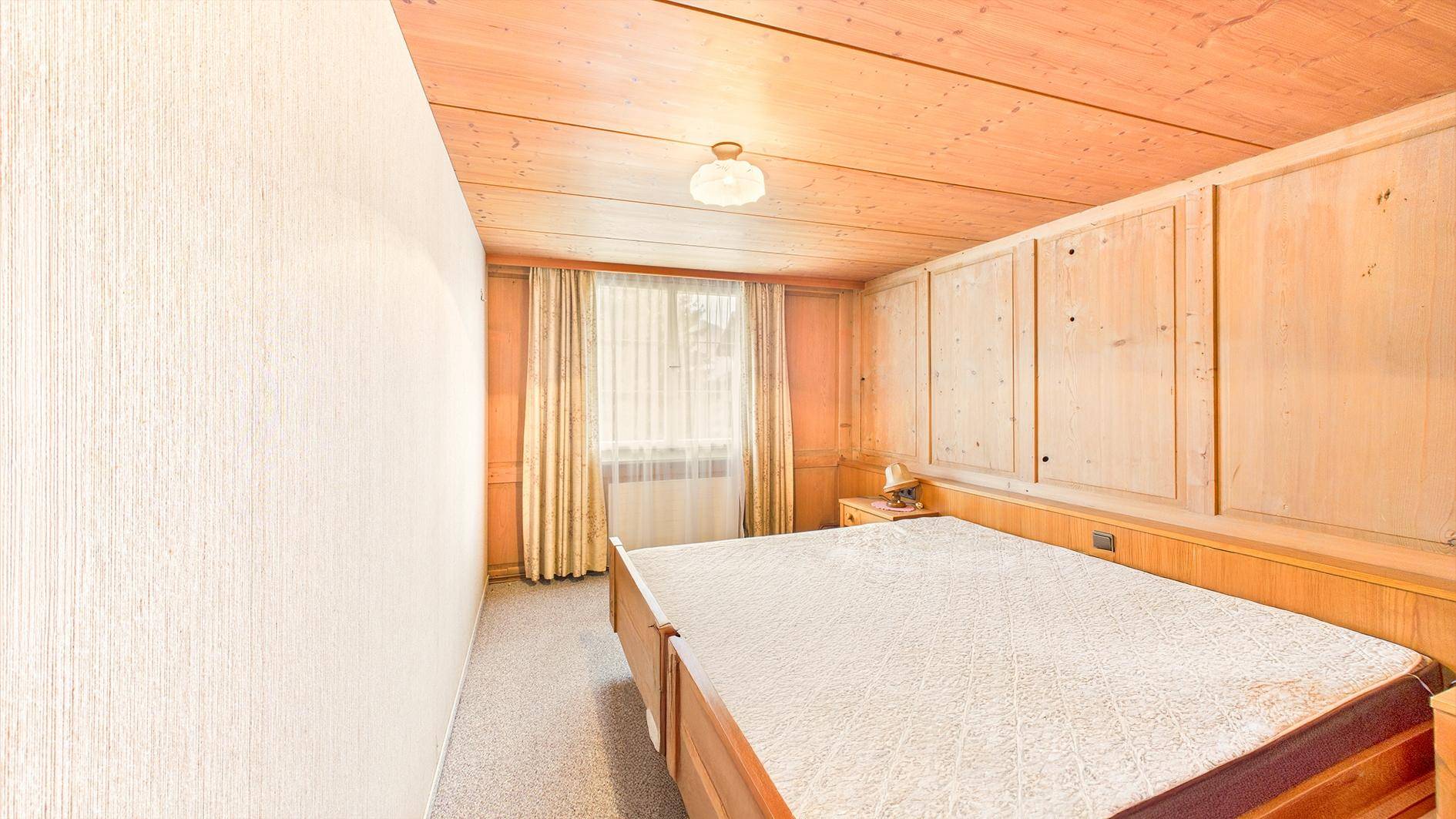 Gemütliches Schlafzimmer mit Holztäfelung, Doppelbett und Fenster, in traditionellem Stil.