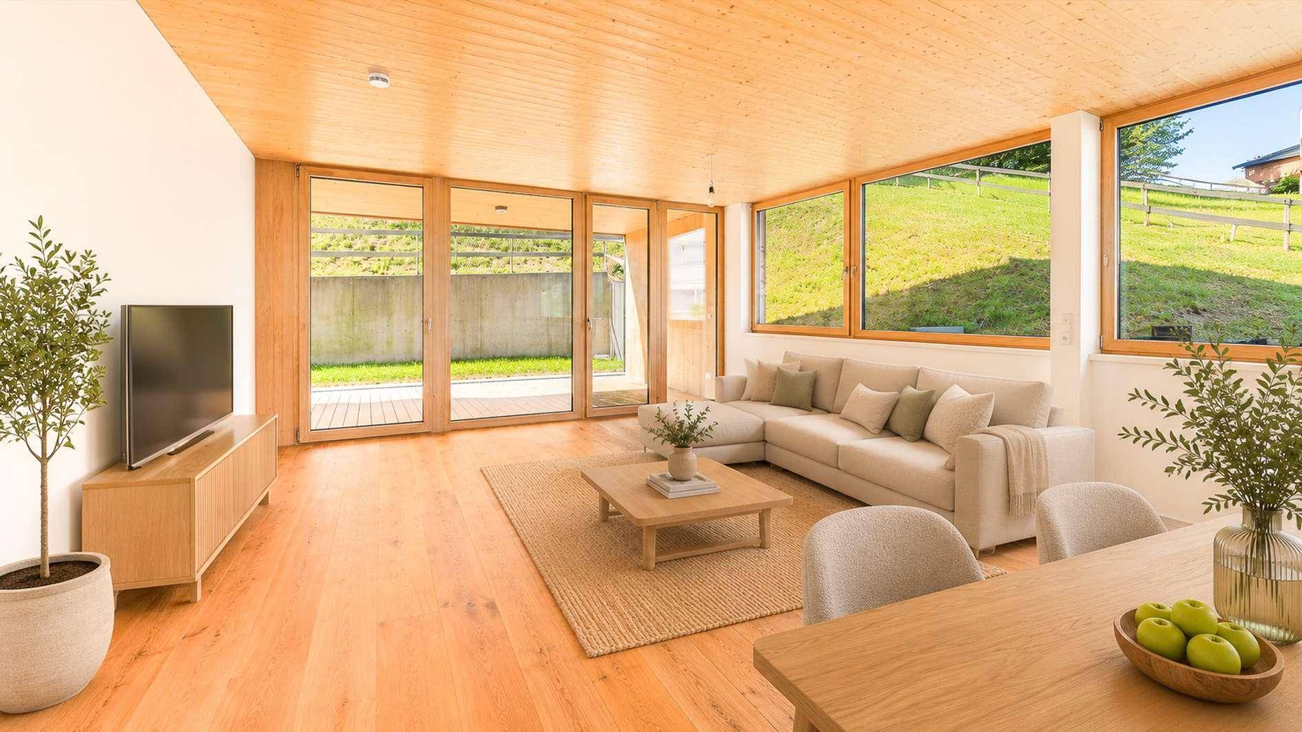 Geräumiger Wohnbereich mit Holzboden, großen Fenstern und Zugang zur Terrasse mit Blick auf die Natur.