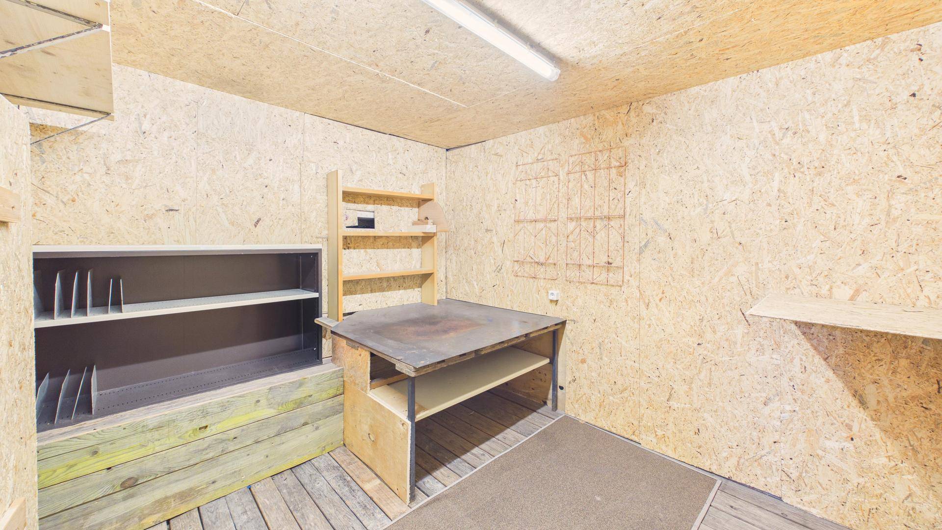 Praktischer Werkstatt- oder Abstellraum mit Holzverkleidung und Regalsystemen.