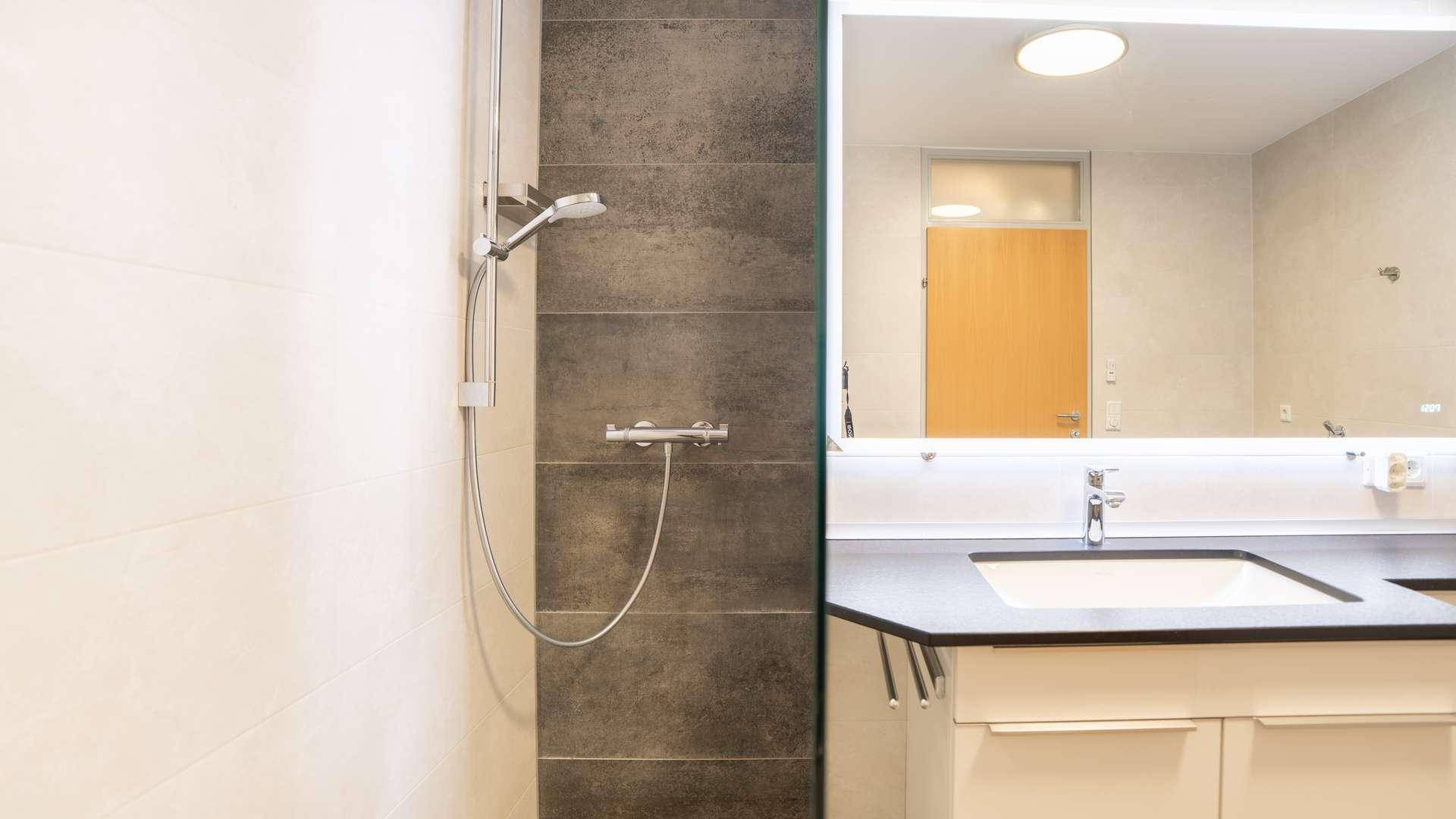 Elegante begehbare Dusche mit dunklen Akzentfliesen in einem modernen Badezimmer.