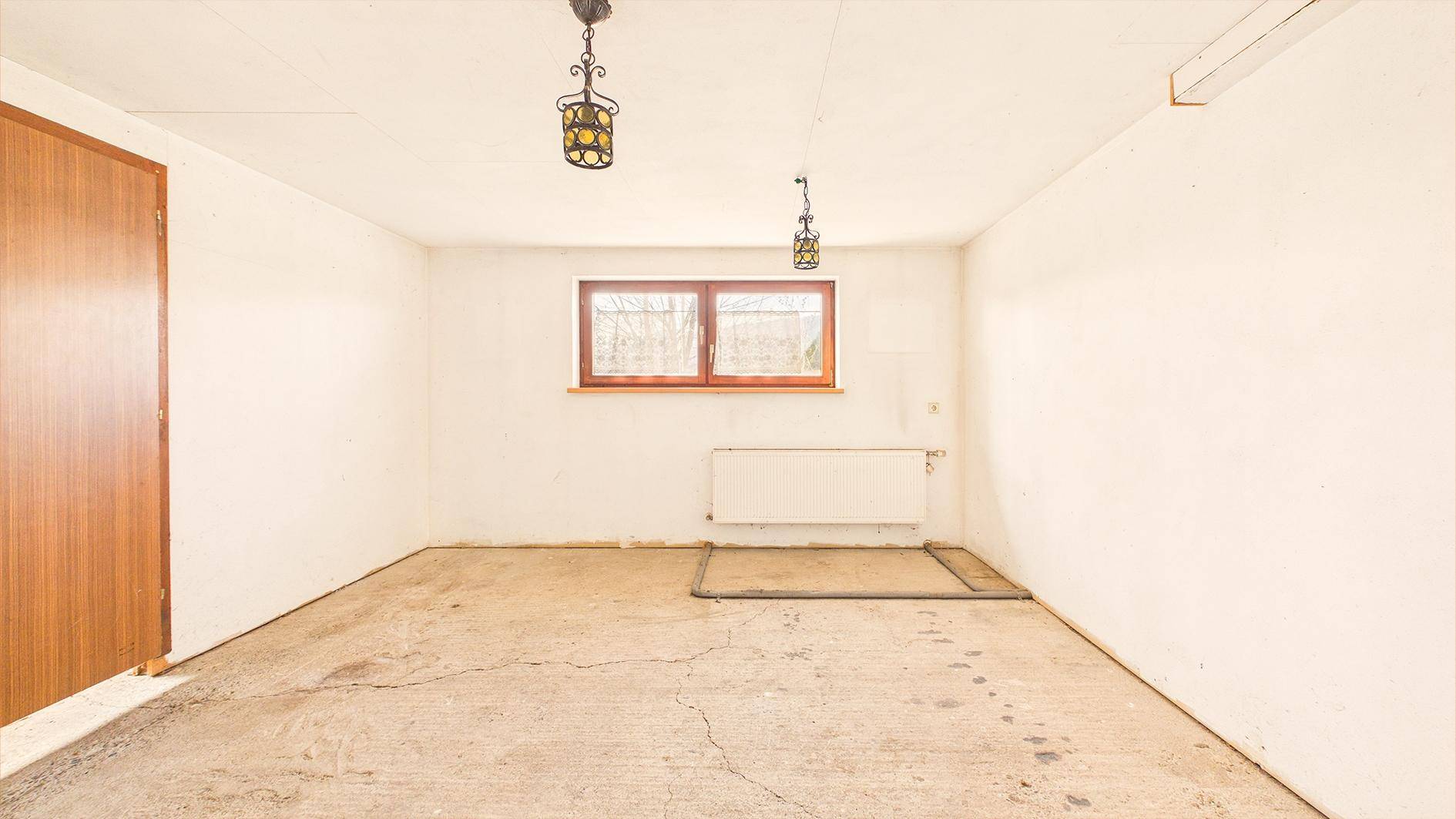 Geräumiger Kellerraum mit Betonboden, weißen Wänden und einem Fenster für Belüftung.