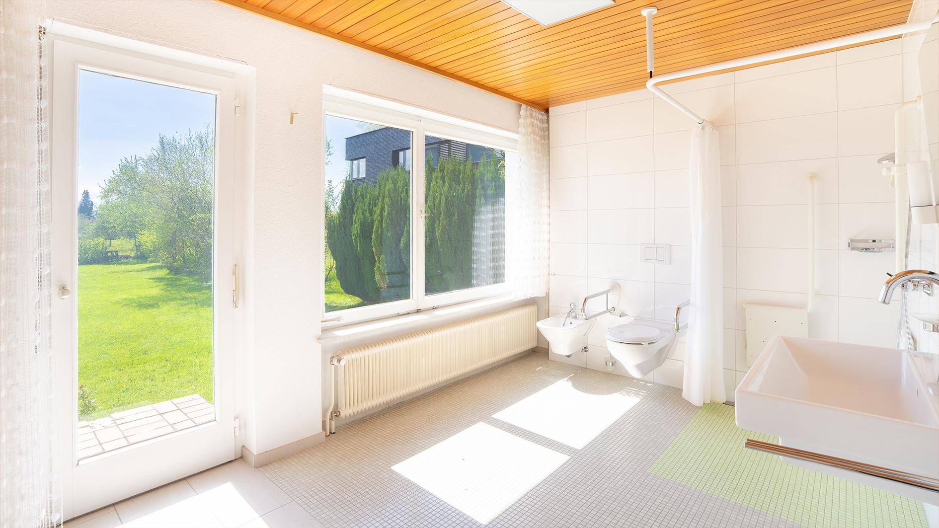Geräumiges Badezimmer mit Dusche, Bidet und großem Fenster mit Gartenblick.