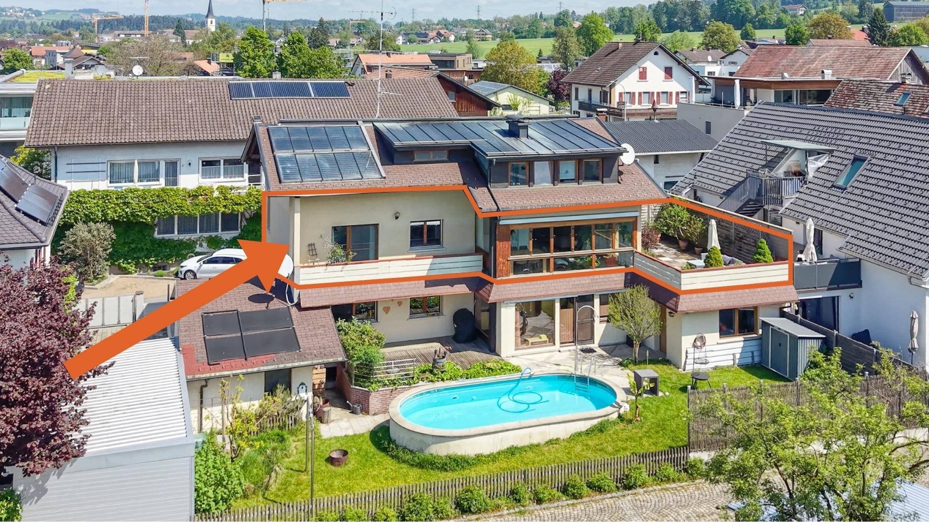 Luftaufnahme eines Hauses mit Pool, Garten und Photovoltaikanlage auf dem Dach.