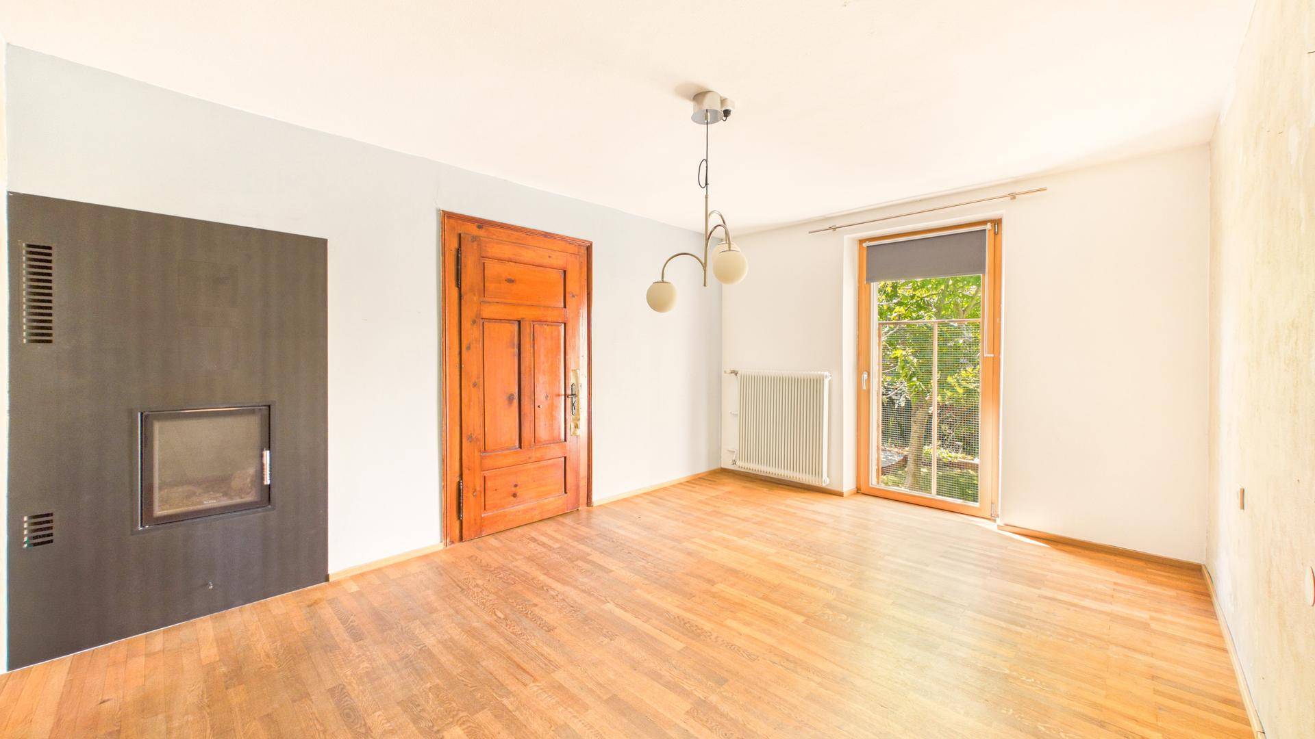 Helles Wohnzimmer mit Holzboden, modernem Kamin und Blick ins Grüne.
