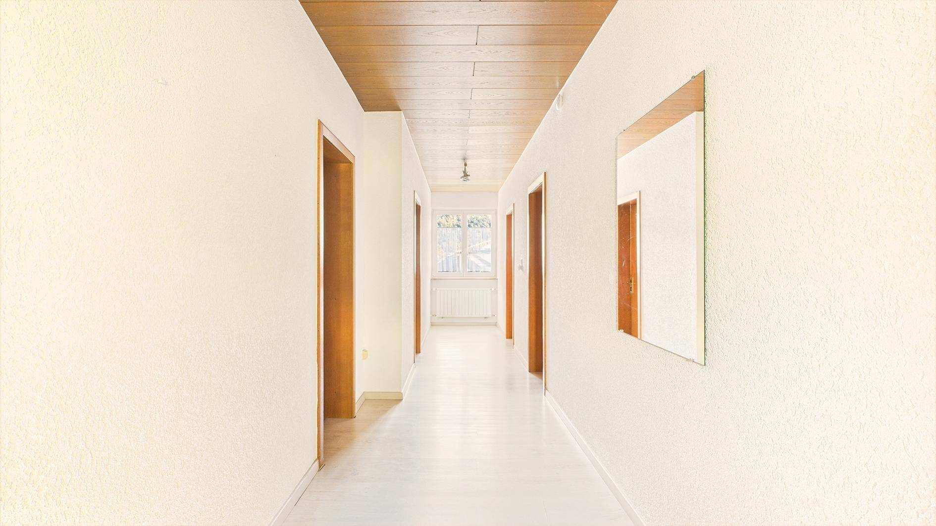Langer Flur mit Holztäfelung an der Decke und mehreren Türen.