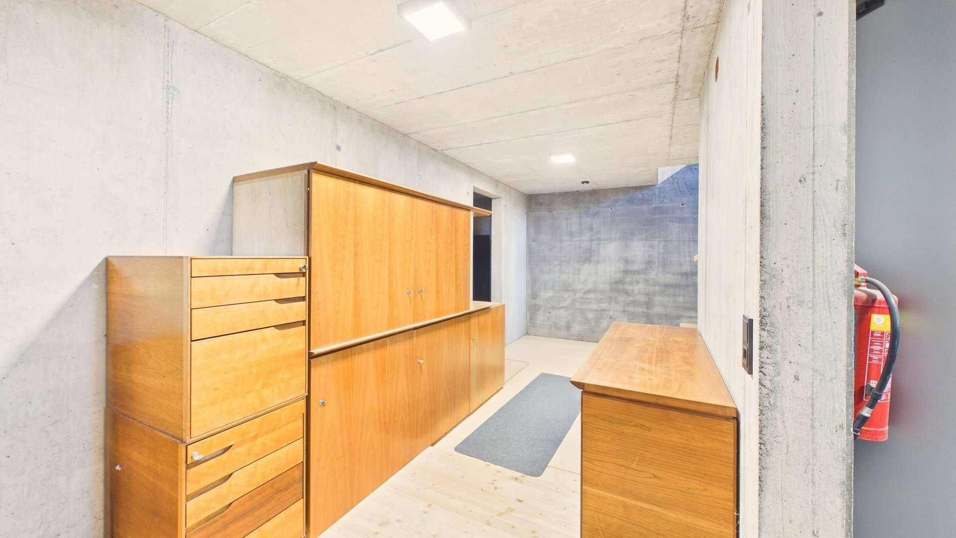 Kellerflur mit Sichtbetonwänden und praktischen Holzschränken für zusätzlichen Stauraum.