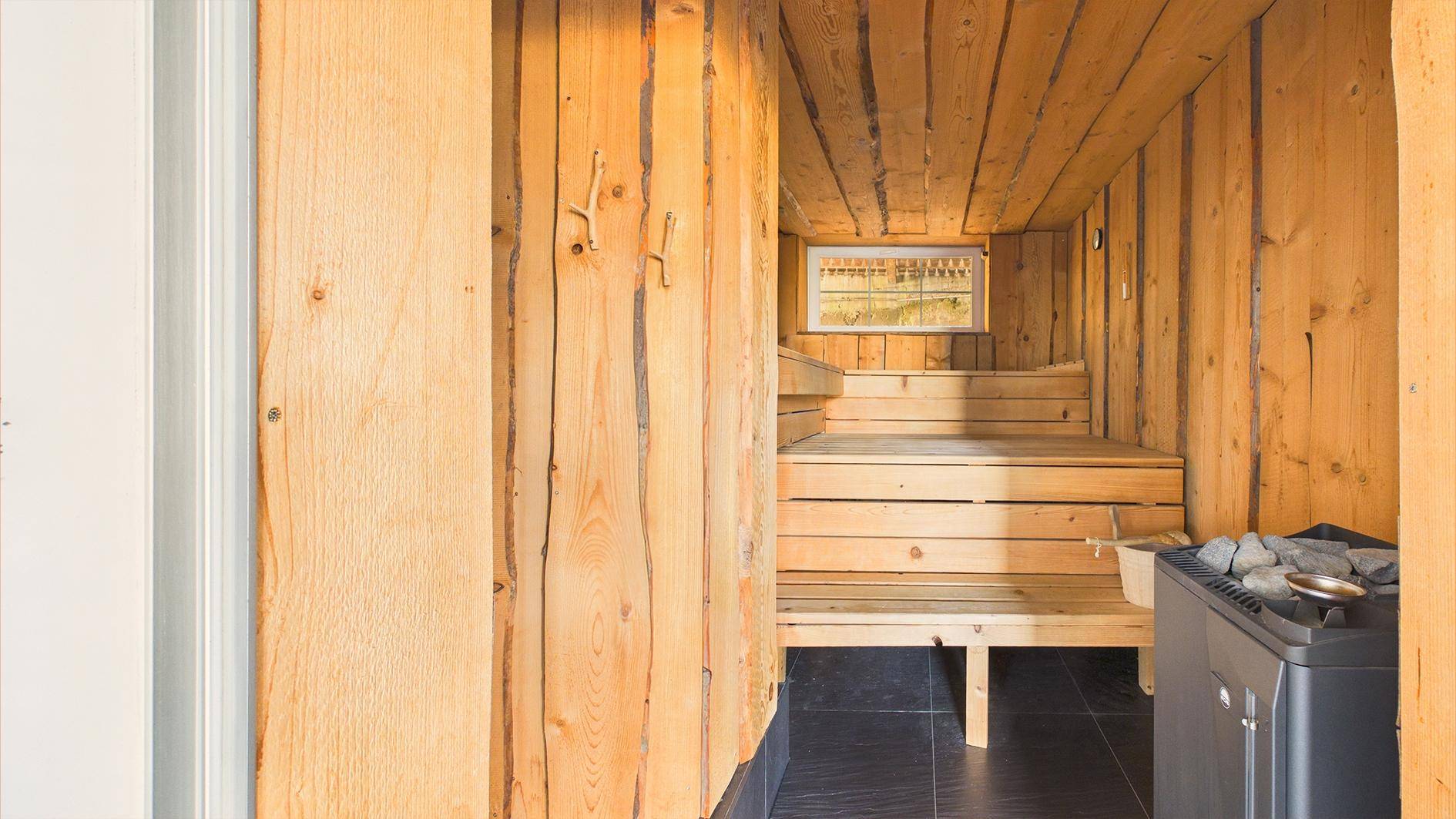 Traditionelle Holzsauna mit Bänken und Saunaofen für entspannende Wellnessmomente.