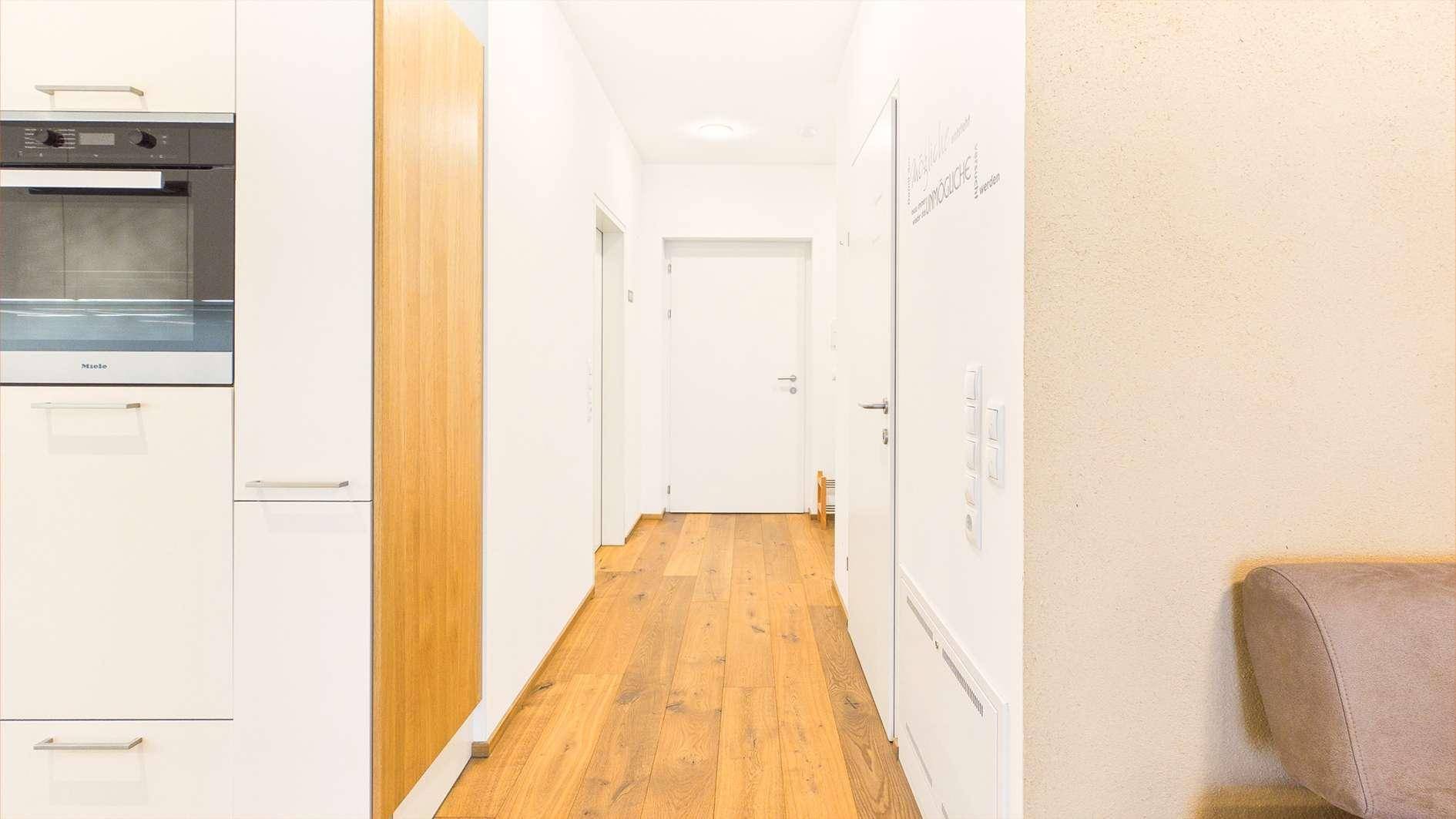 Moderner Flur mit Holzboden, weißen Wänden und integrierten Schränken.