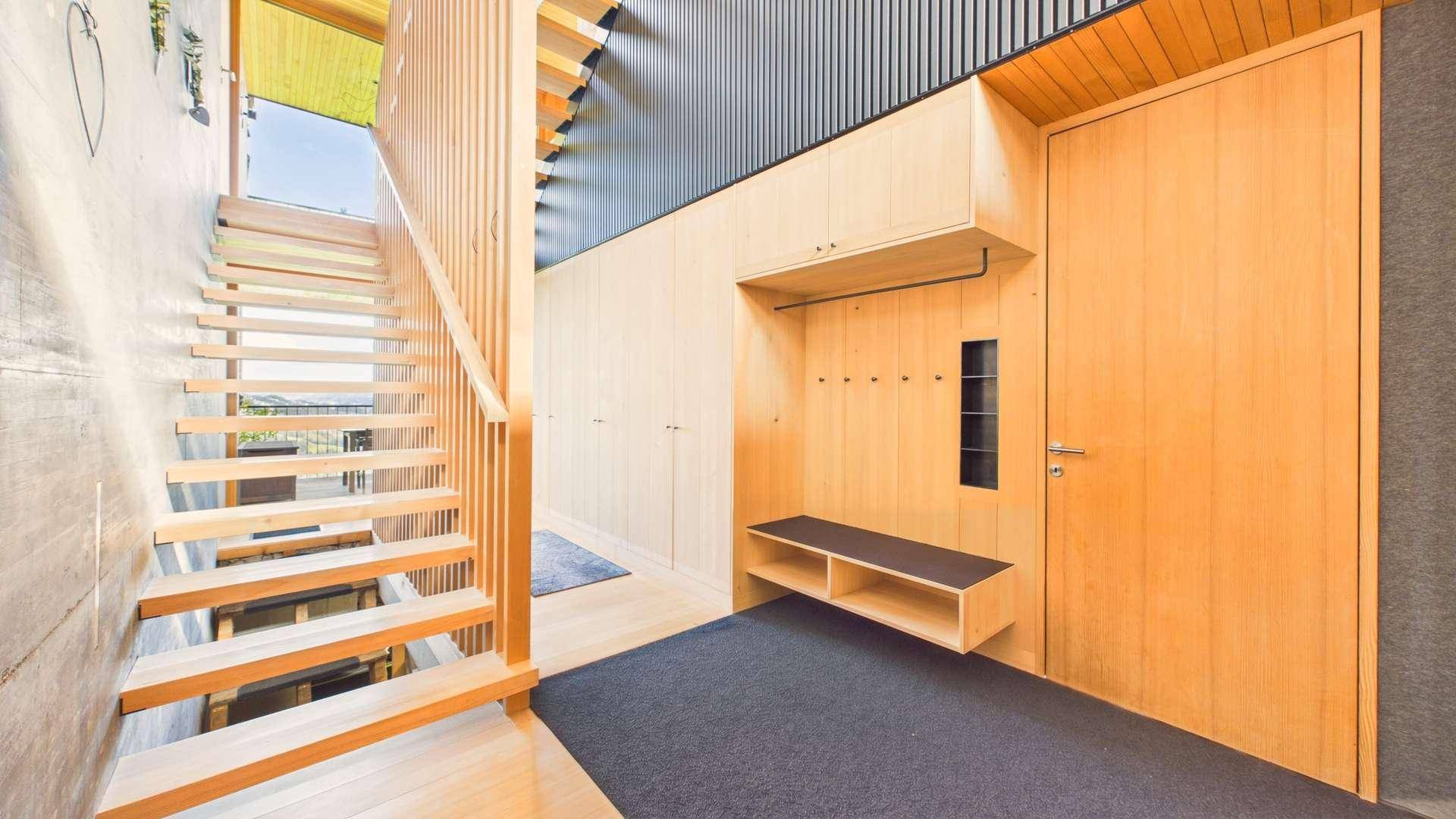 Heller Eingangsbereich mit Holztreppe, Garderobe und integrierten Schränken für Stauraum.