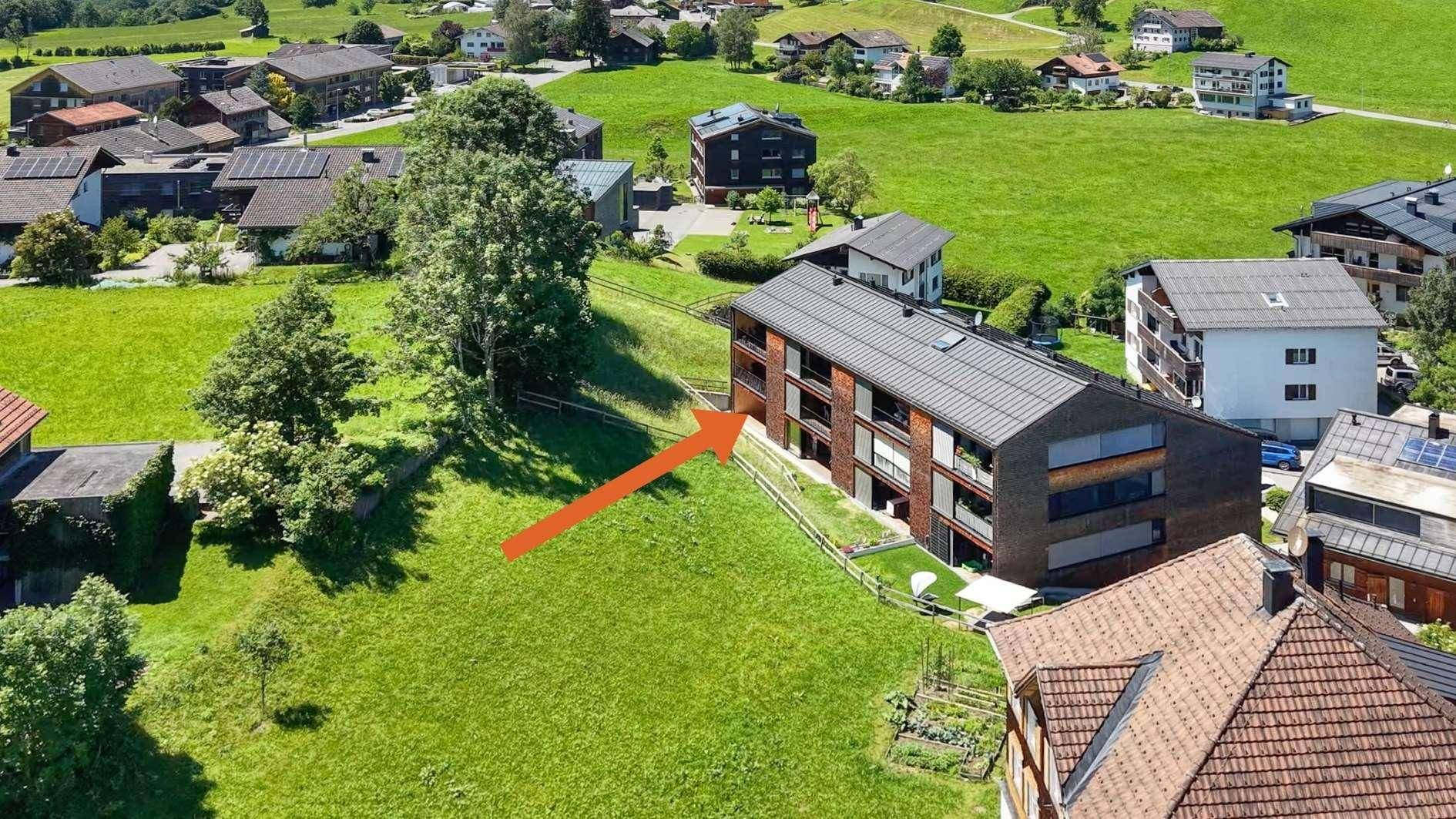 Nahaufnahme aus der Vogelperspektive einer Wohnanlage inmitten grüner Landschaft.