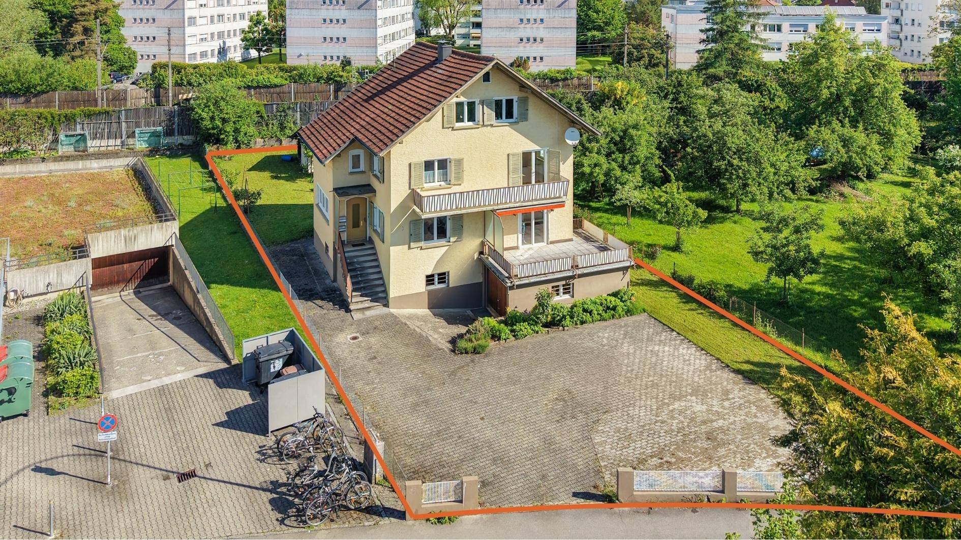 Luftaufnahme des Hauses mit großem Grundstück, Garten und gepflasterten Zufahrten, umrandet.
