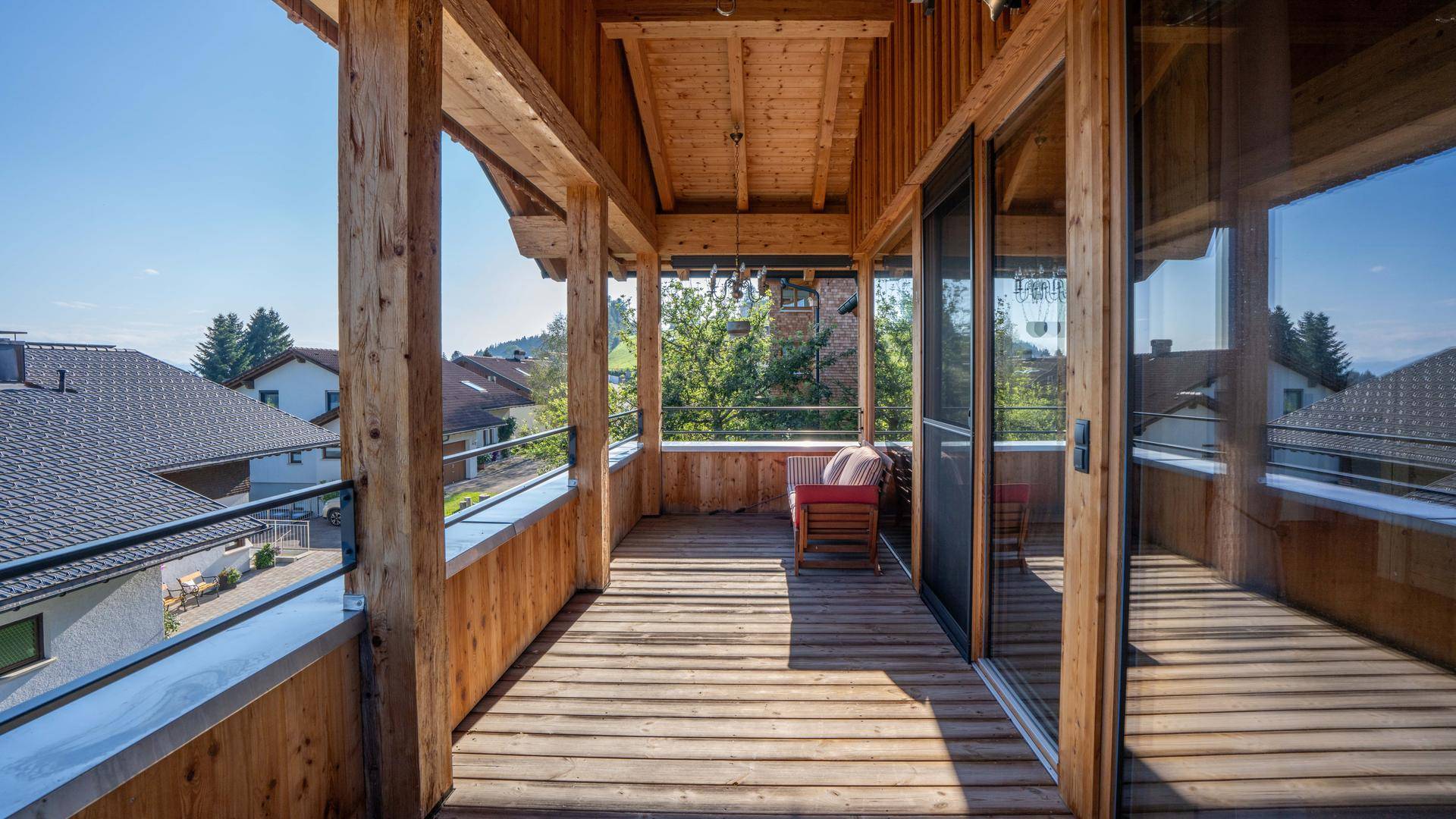 Geräumiger Holzbalkon mit Sitzgelegenheit und Blick auf die umliegende Wohngegend.