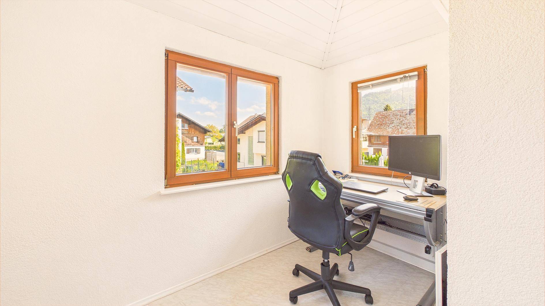 Helles Arbeitszimmer mit Fenster, Schreibtisch und ergonomischem Bürostuhl.