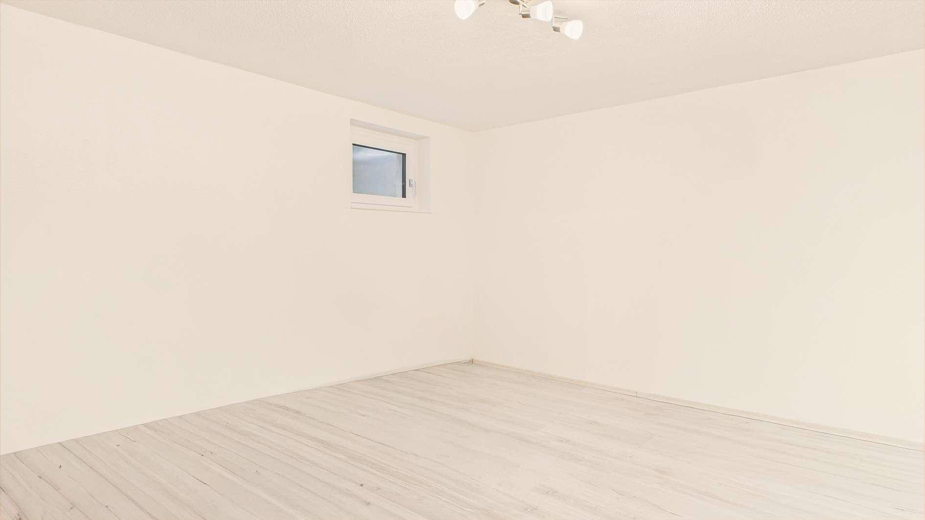 Leerer Raum mit hellem Boden und Fenster, vielseitig nutzbar als Gästezimmer oder Abstellraum.