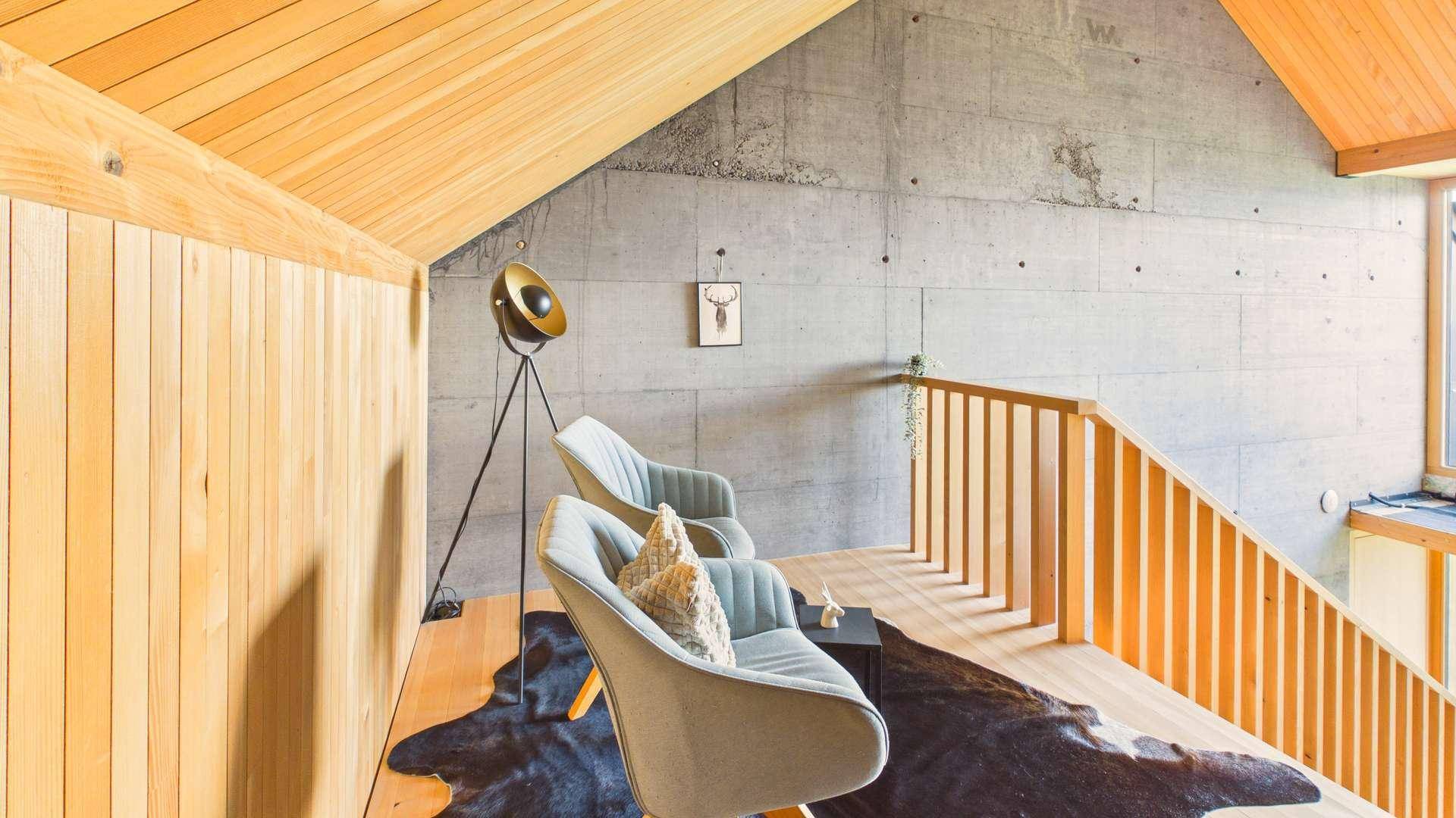 Heller Flurbereich mit Holzboden, Betonelementen und modernen Sitzgelegenheiten.
