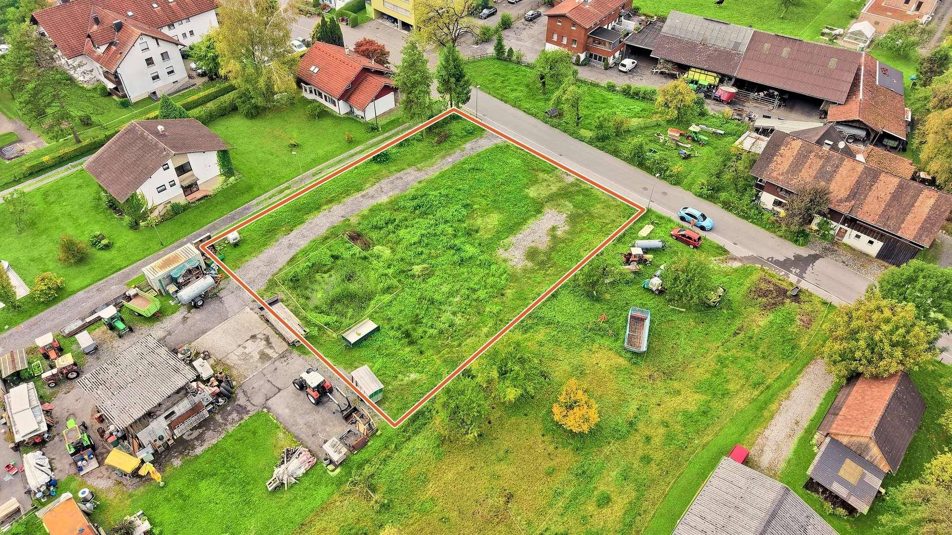 Weitläufige Luftaufnahme eines unbebauten Grundstücks in einer ländlichen Wohngegend mit umliegenden Gebäuden.