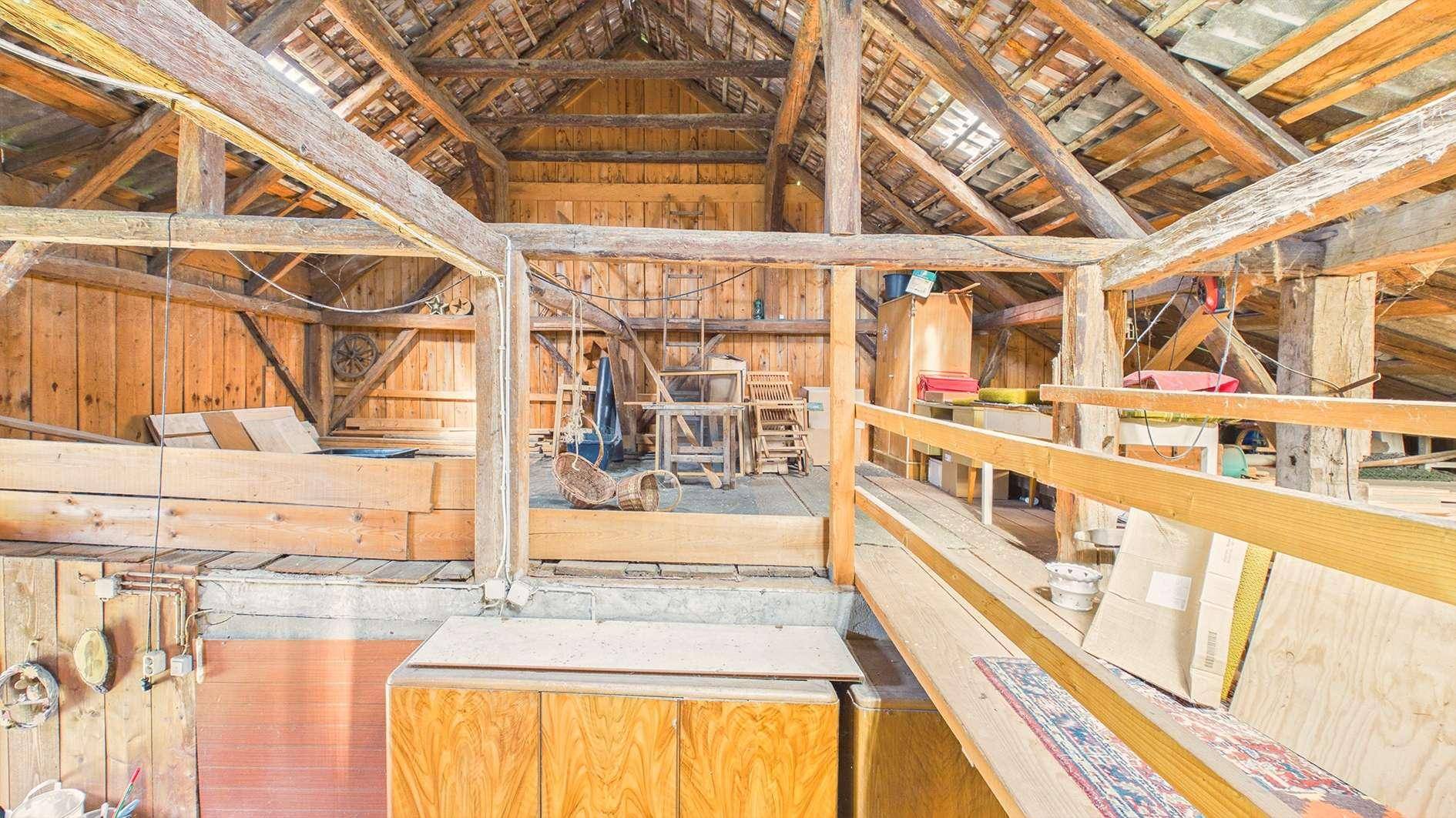 Dachboden mit sichtbaren Holzbalken und viel Stauraum unter dem Dach.